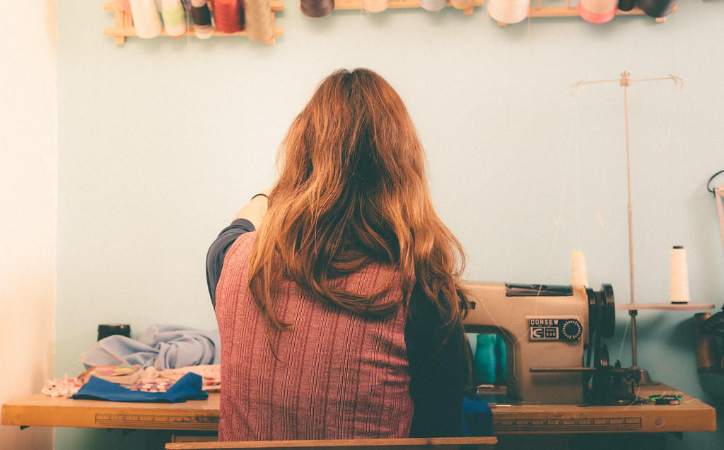 Mujer sentada de espalda frente a máquina de coser