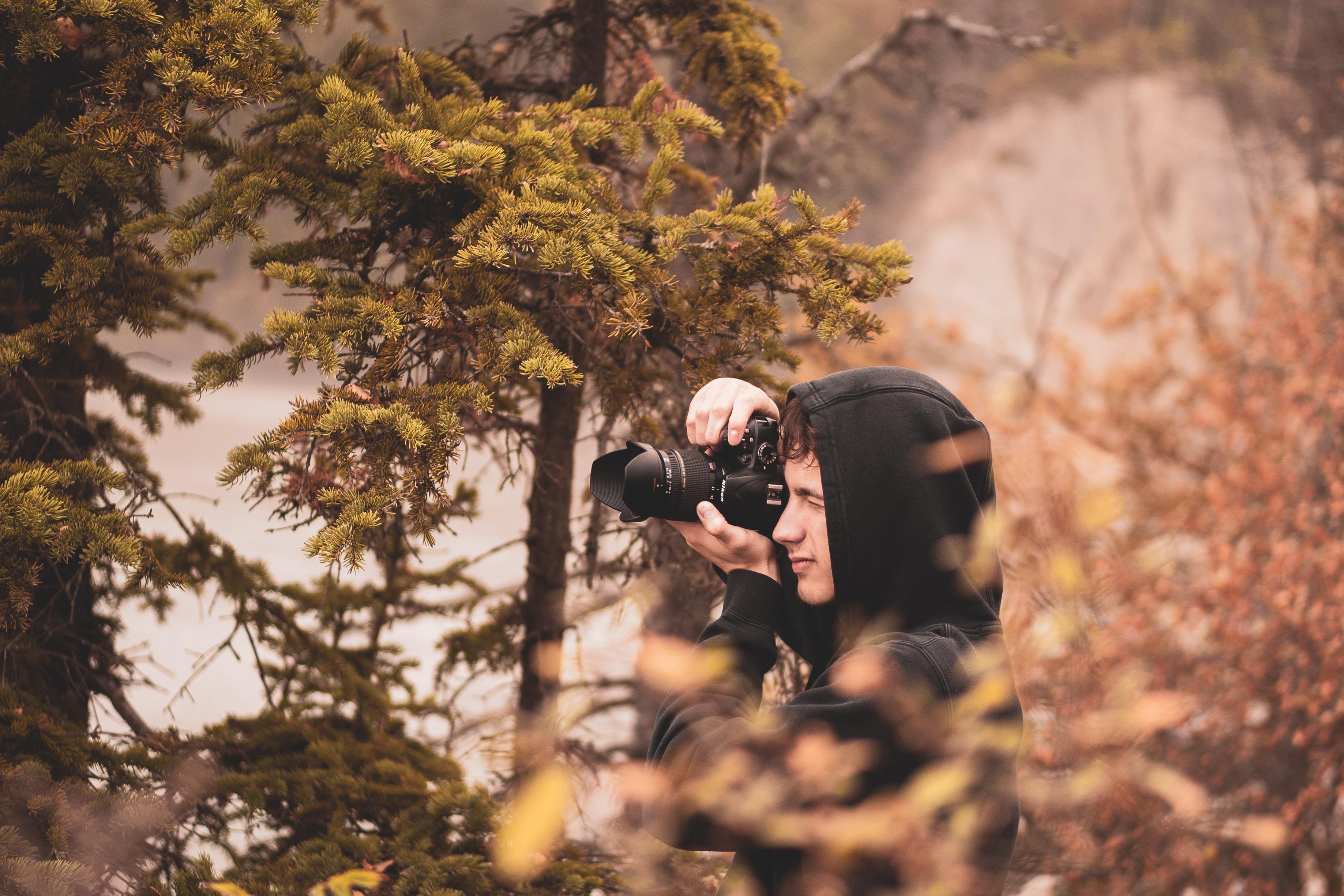 Joven tomando foto en bosque