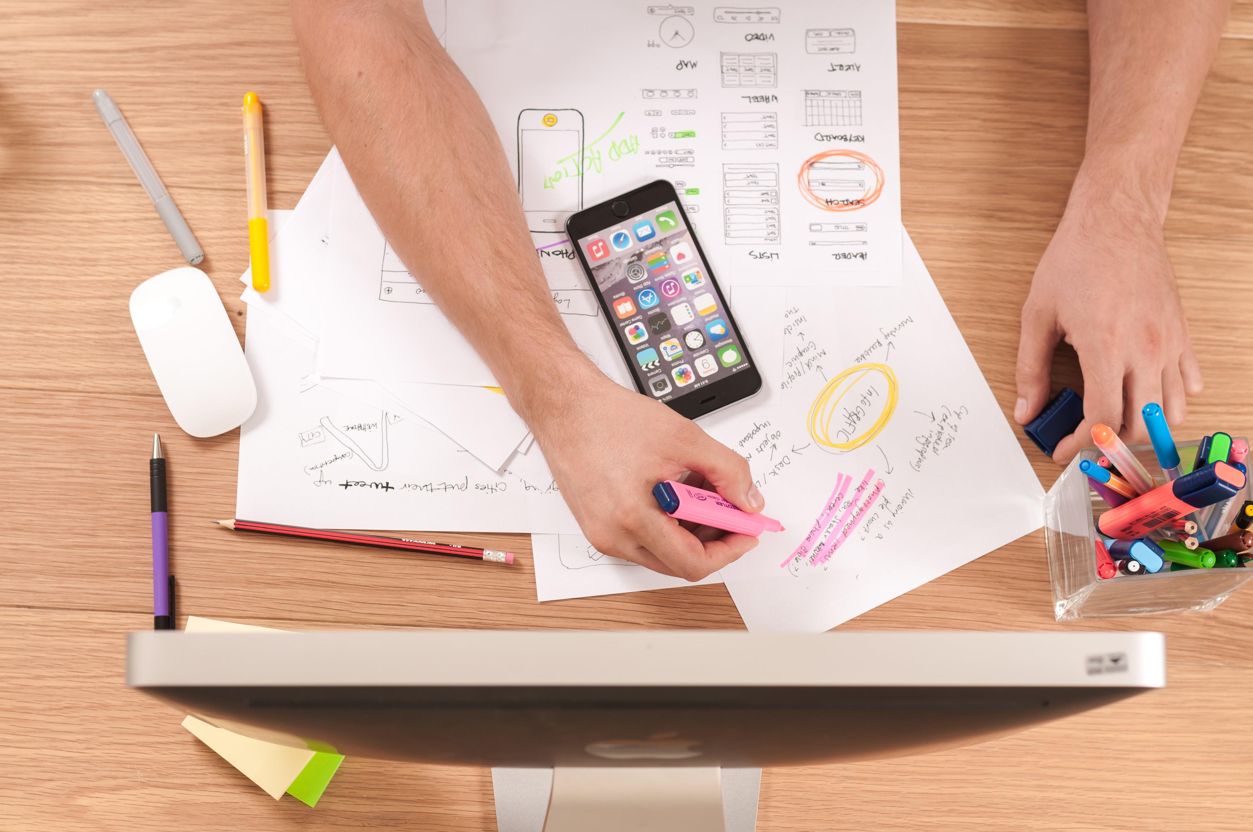 Lugar de estudio con apuntes, smartphone y computador de escritorio