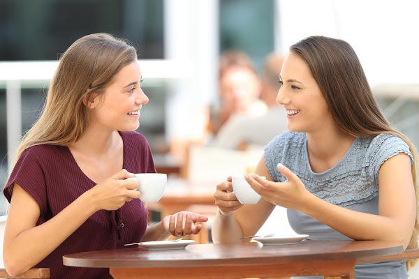 Mujeres sonriendo mientras sostienen tazas de café