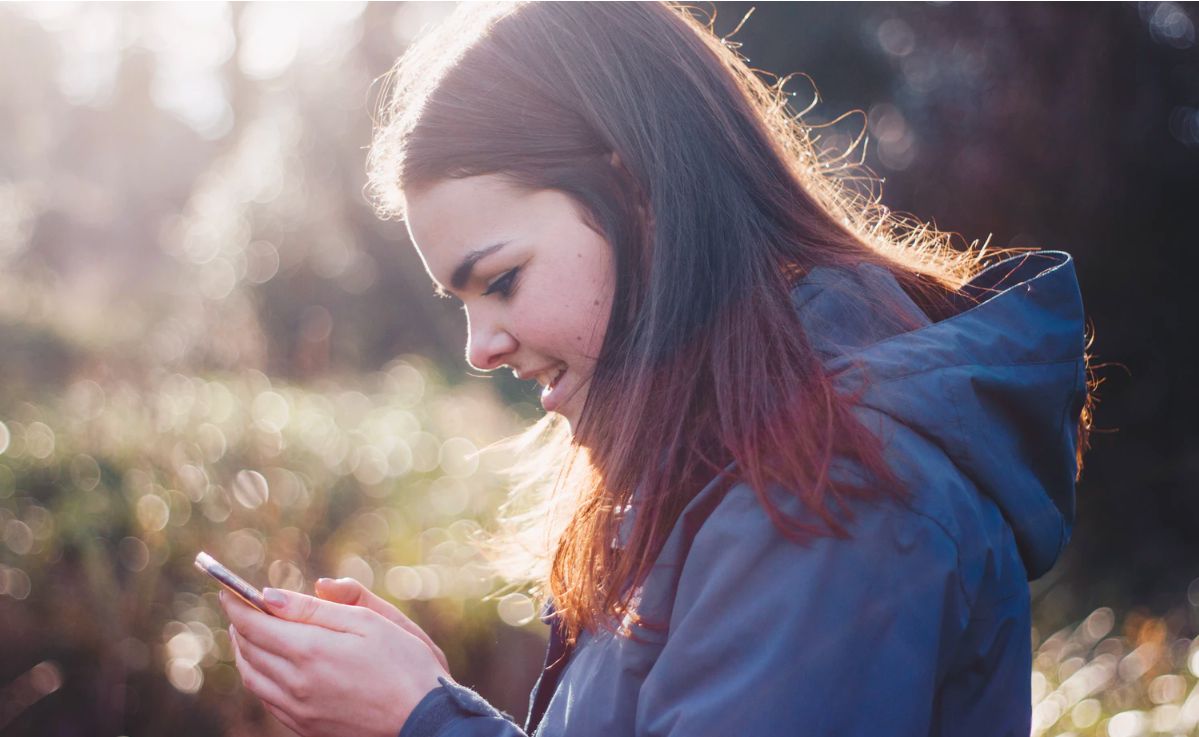 Mujer joven mirando su celular al aire libre