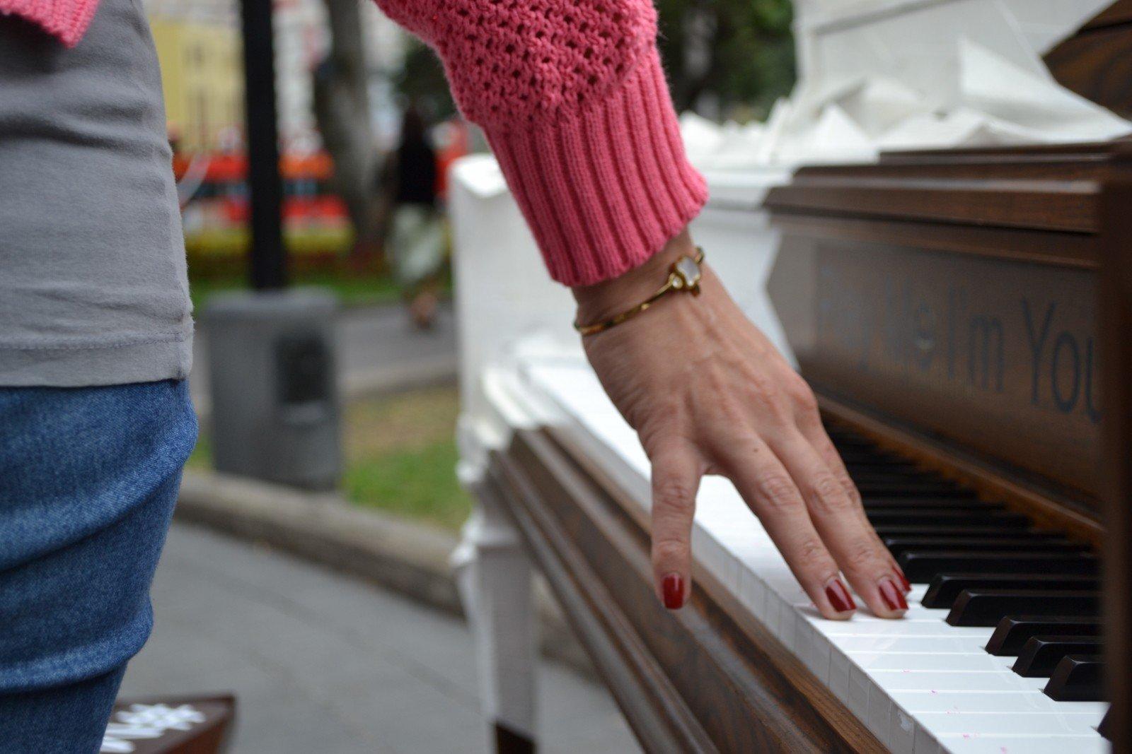 Mujer apoya mano en piano público