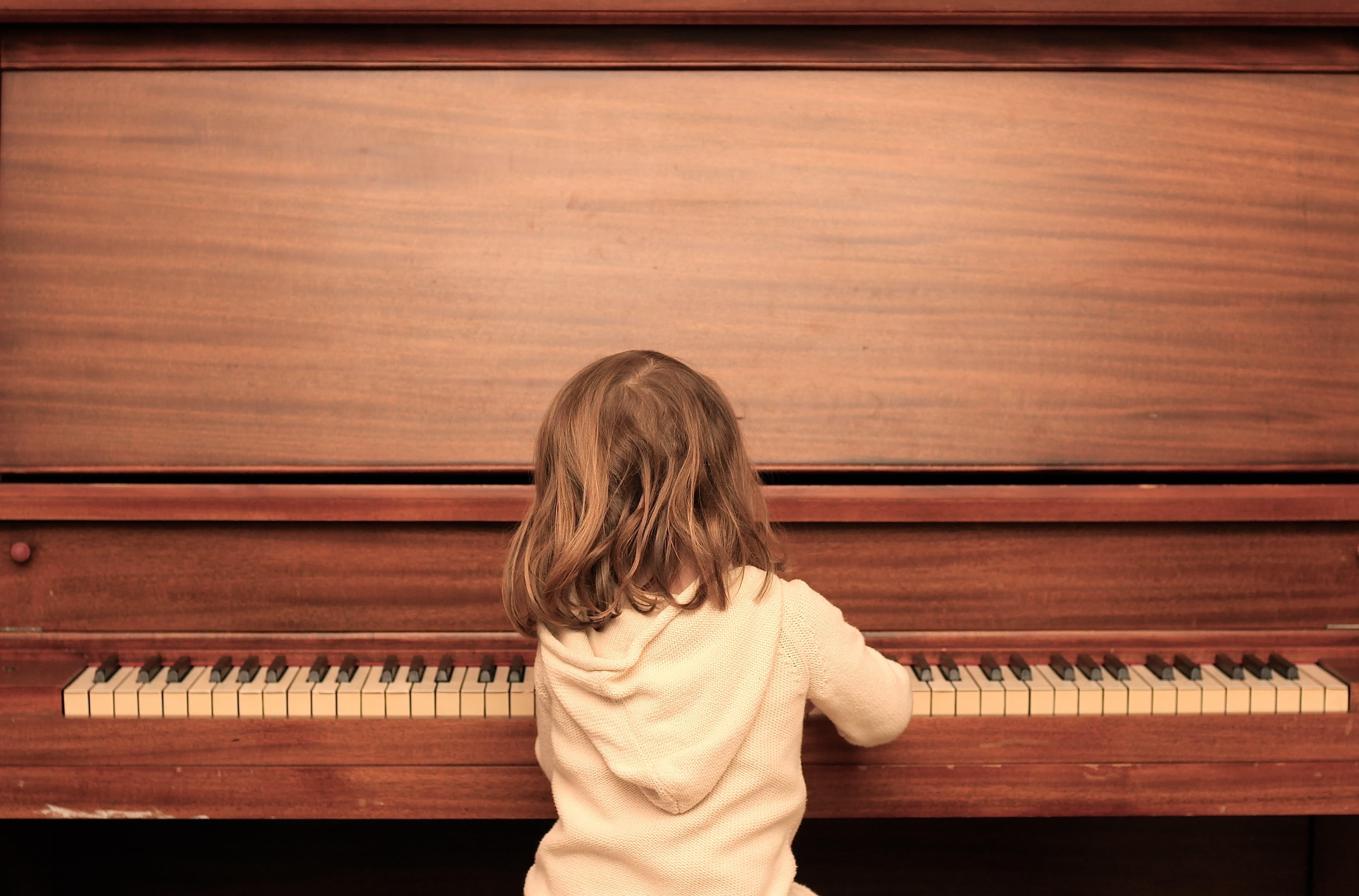 Niña toca piano de madera