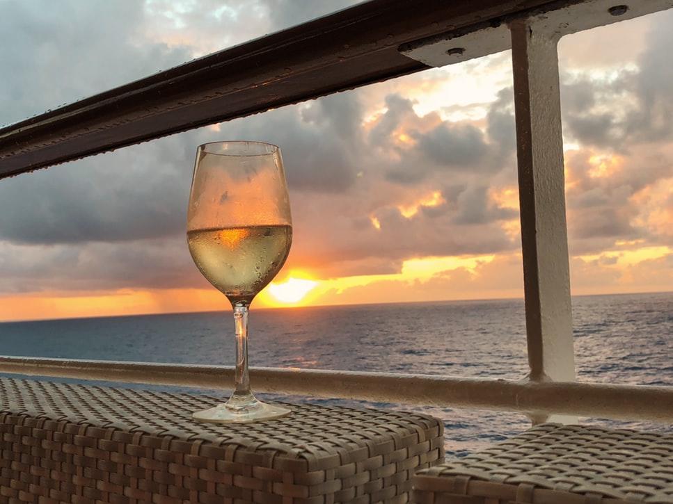 Puesta de sol vista desde crucero con copa de vino blanco