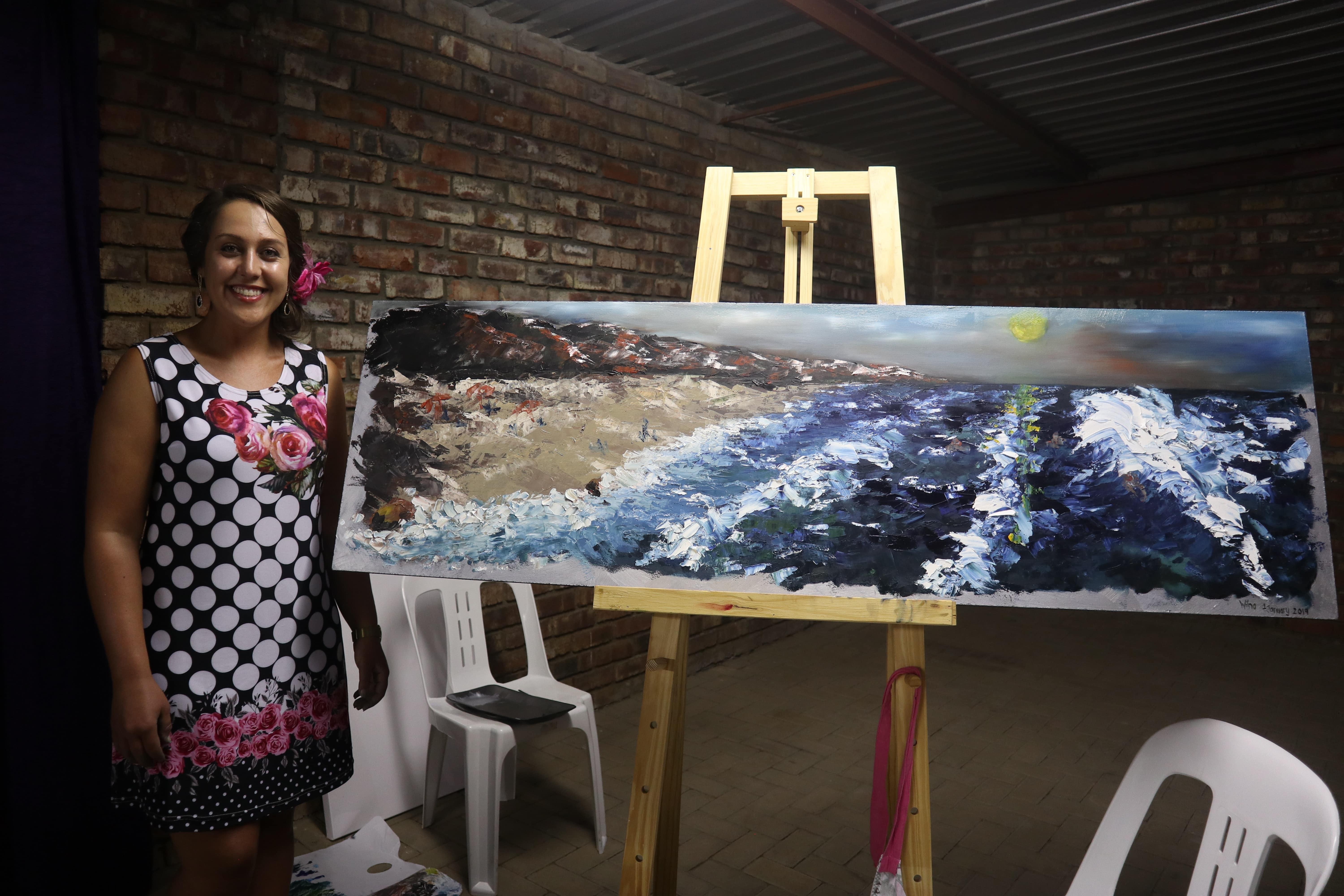 Pintora muestra cuadro de paisaje costero