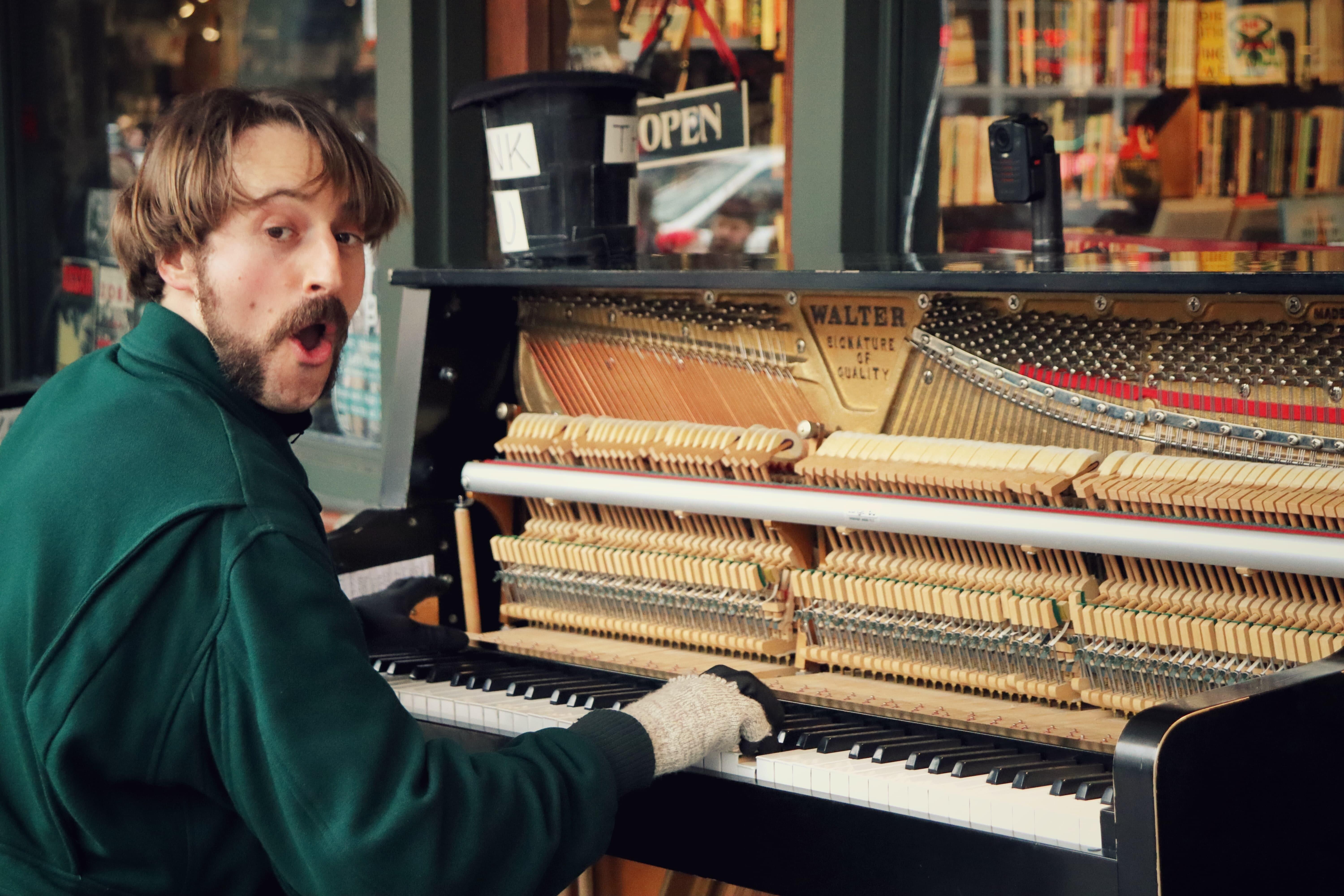 Hombre mira cámara mientras toca piano roto
