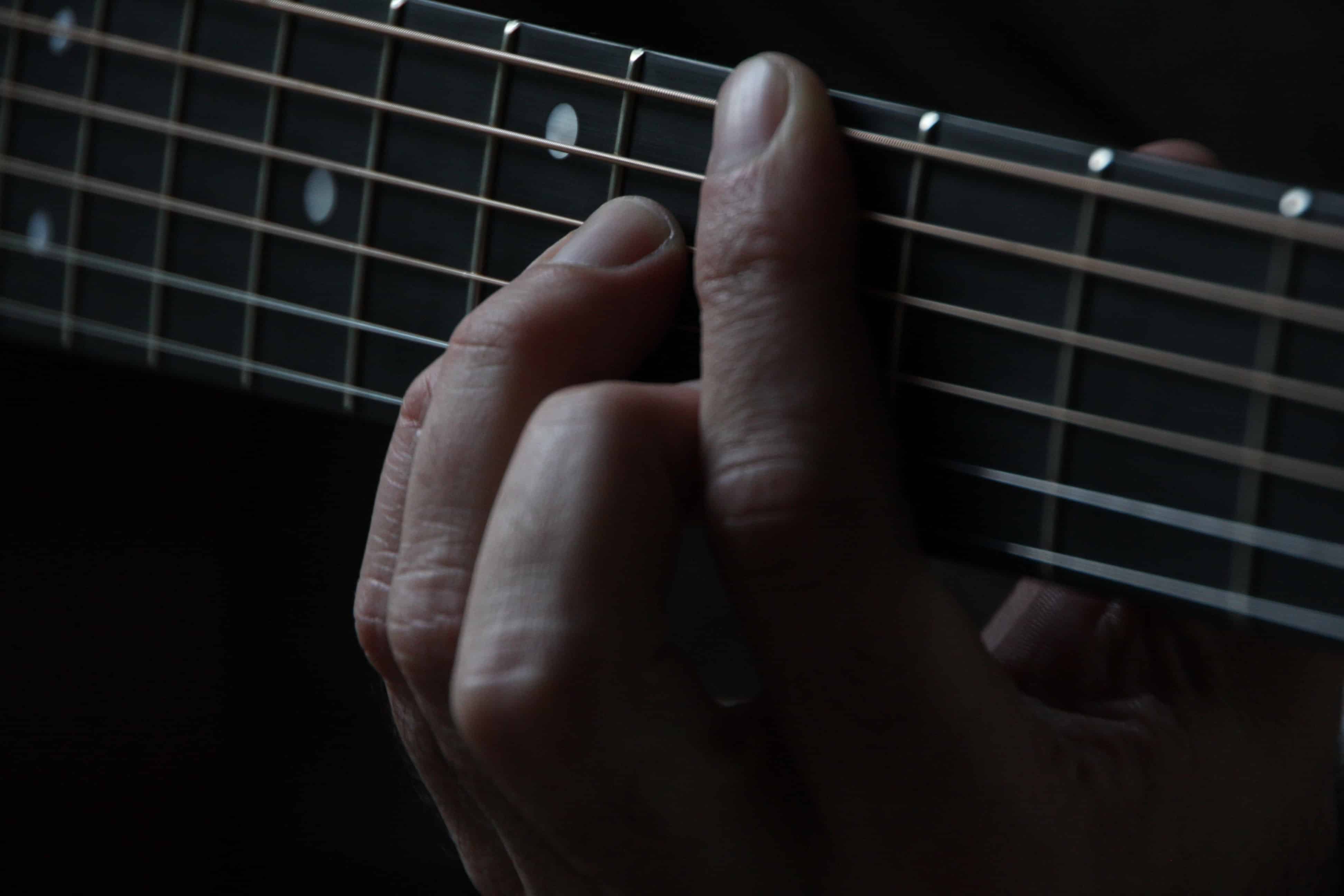 Plano detalle de mano sobre mástil de guitarra