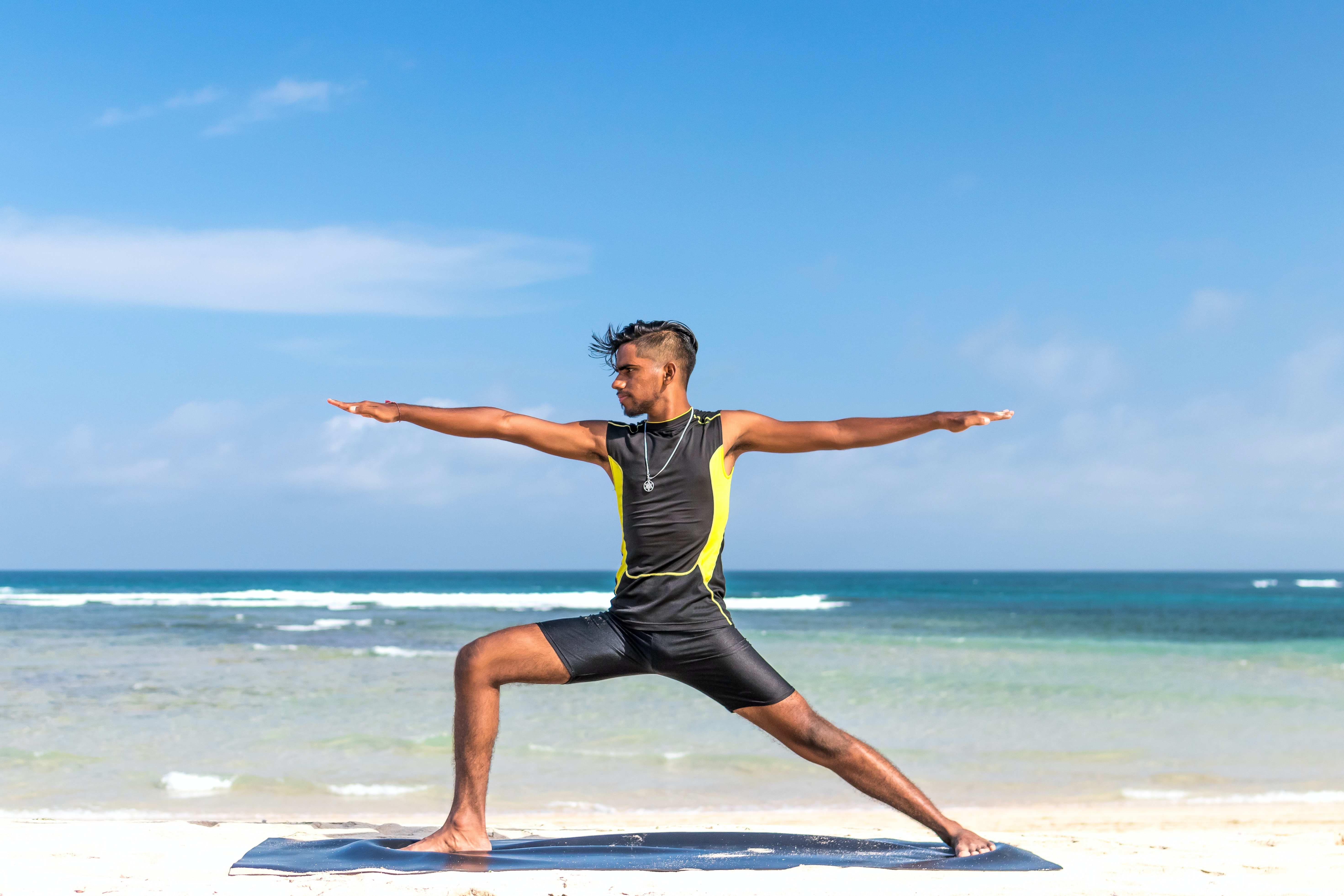 Hombre hace yoga en la playa