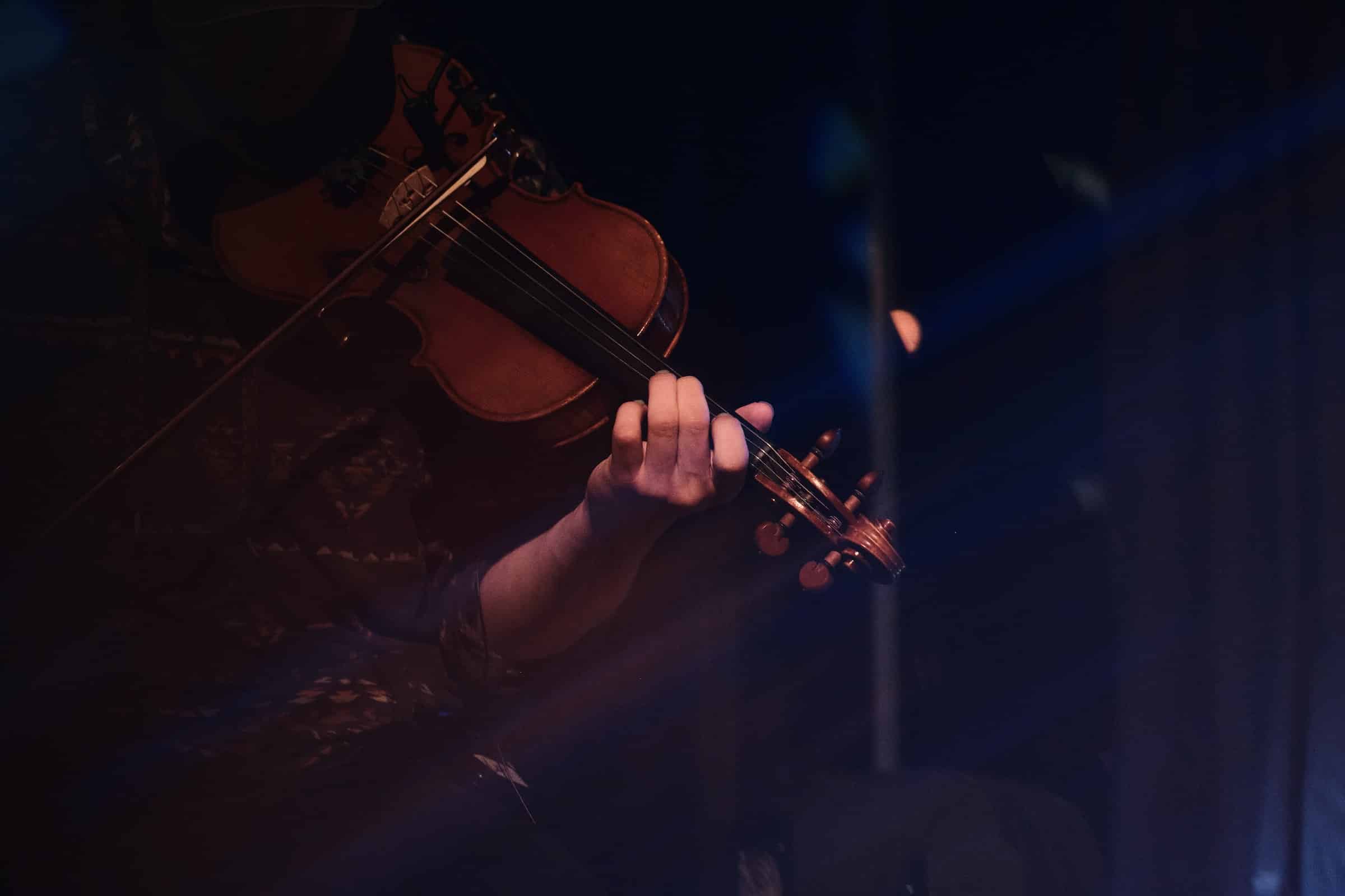 Persona entre sombras ejecutando el violín