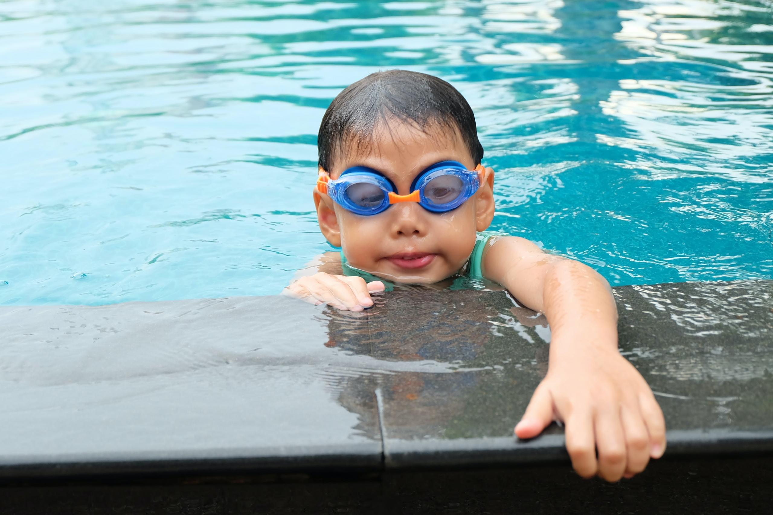 Niño aferrándose a los bordes de la piscina
