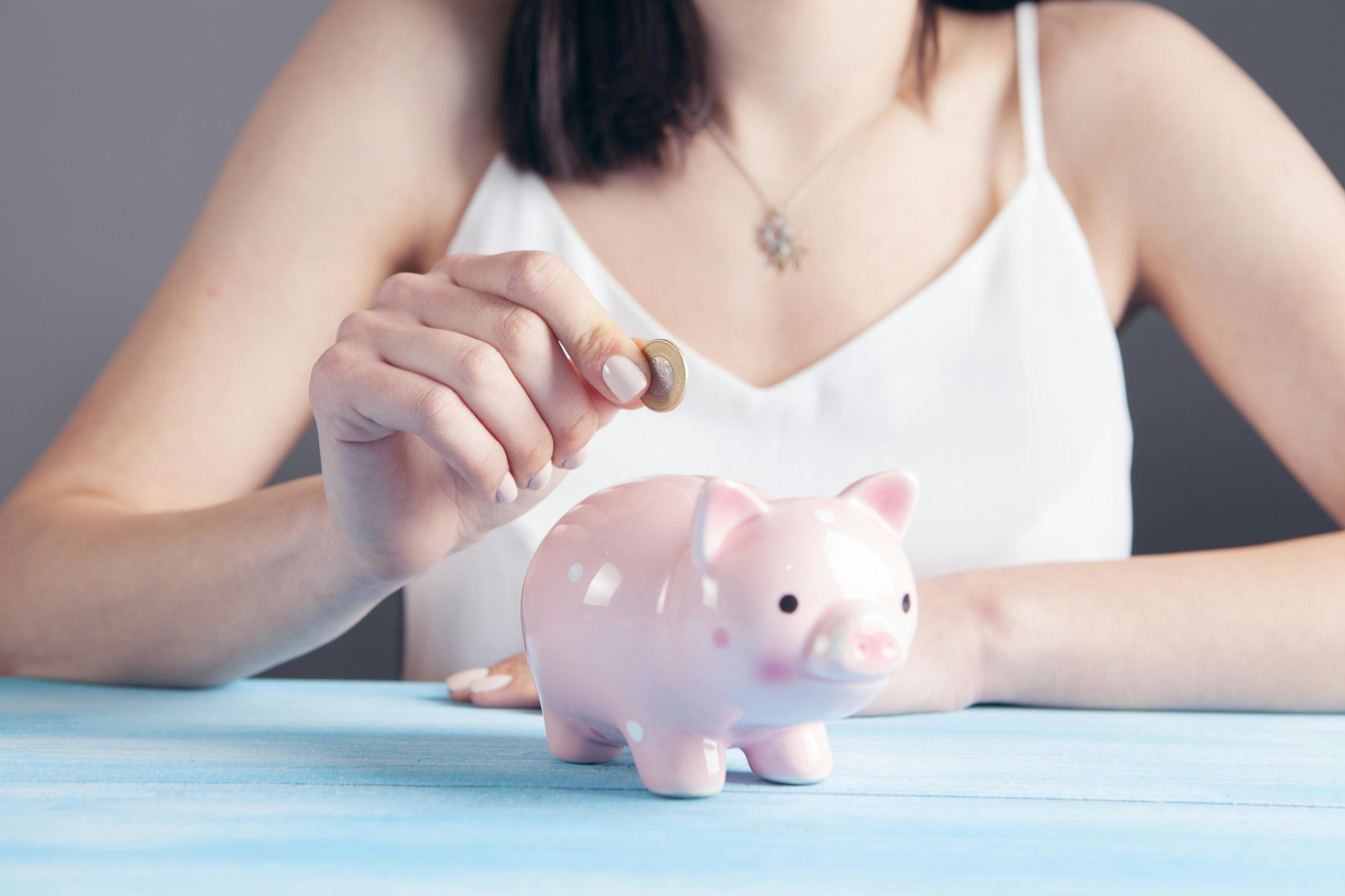 Mujer echando dinero a una alcancía.