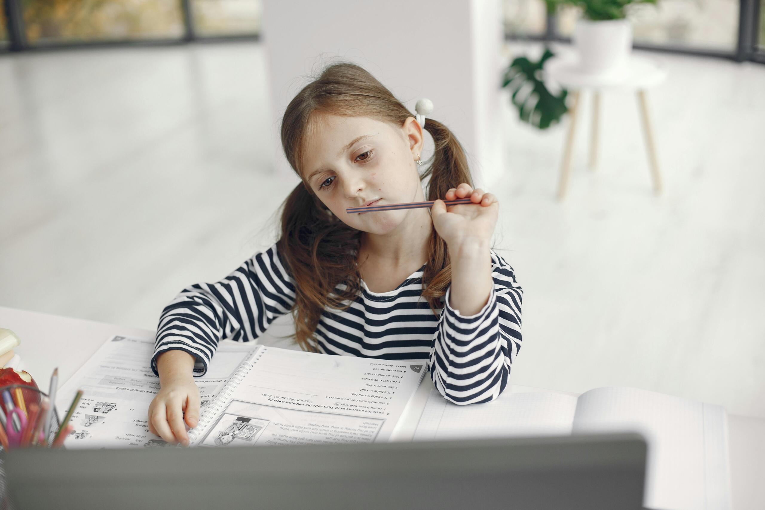 Una niña estudiando sobre su escritorio.