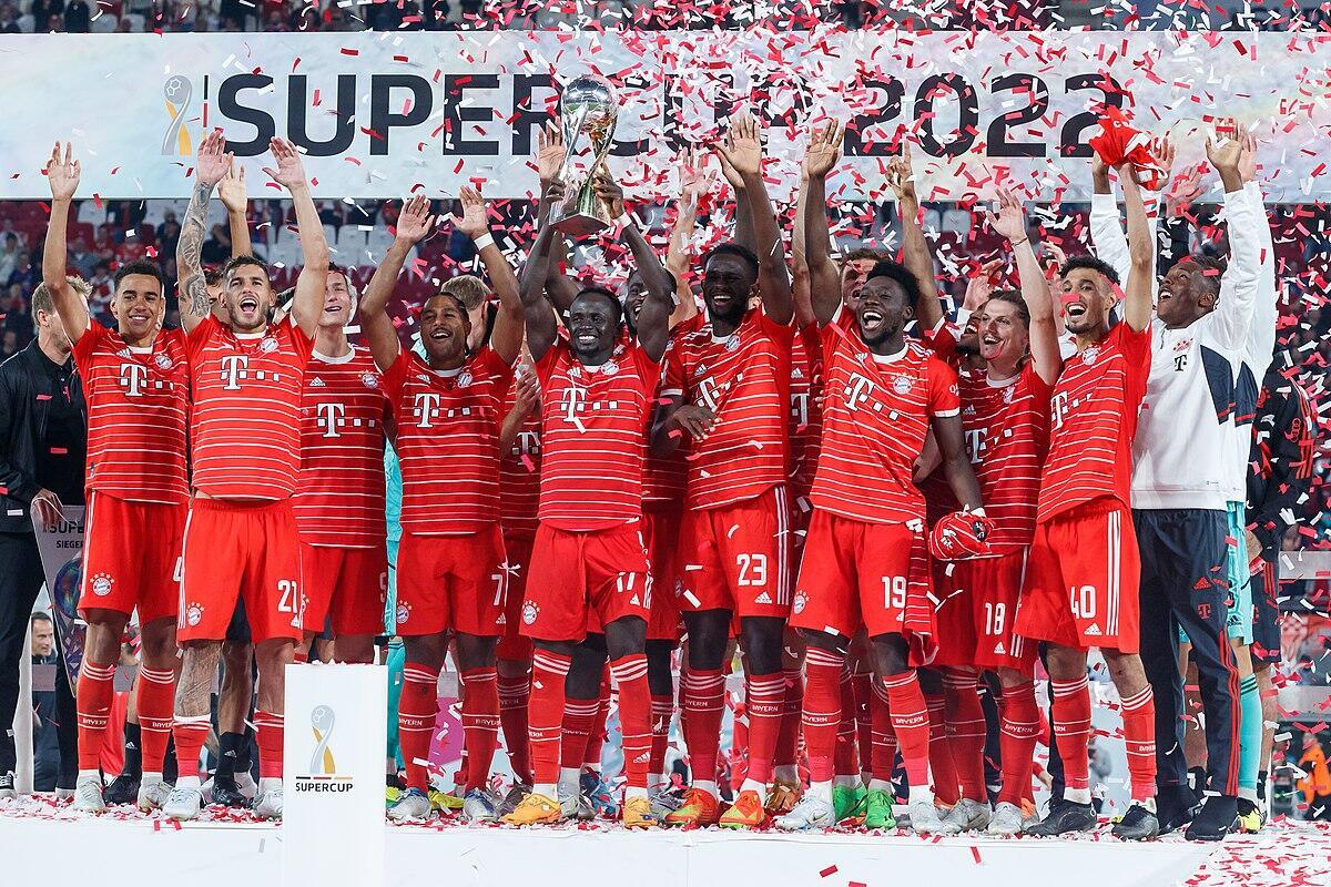 el bayern de municht celebrando una victoria con camisetas rojas sostiene un trofeo en medio de una lluvia de confeti, celebrando su victoria en la Supercopa.