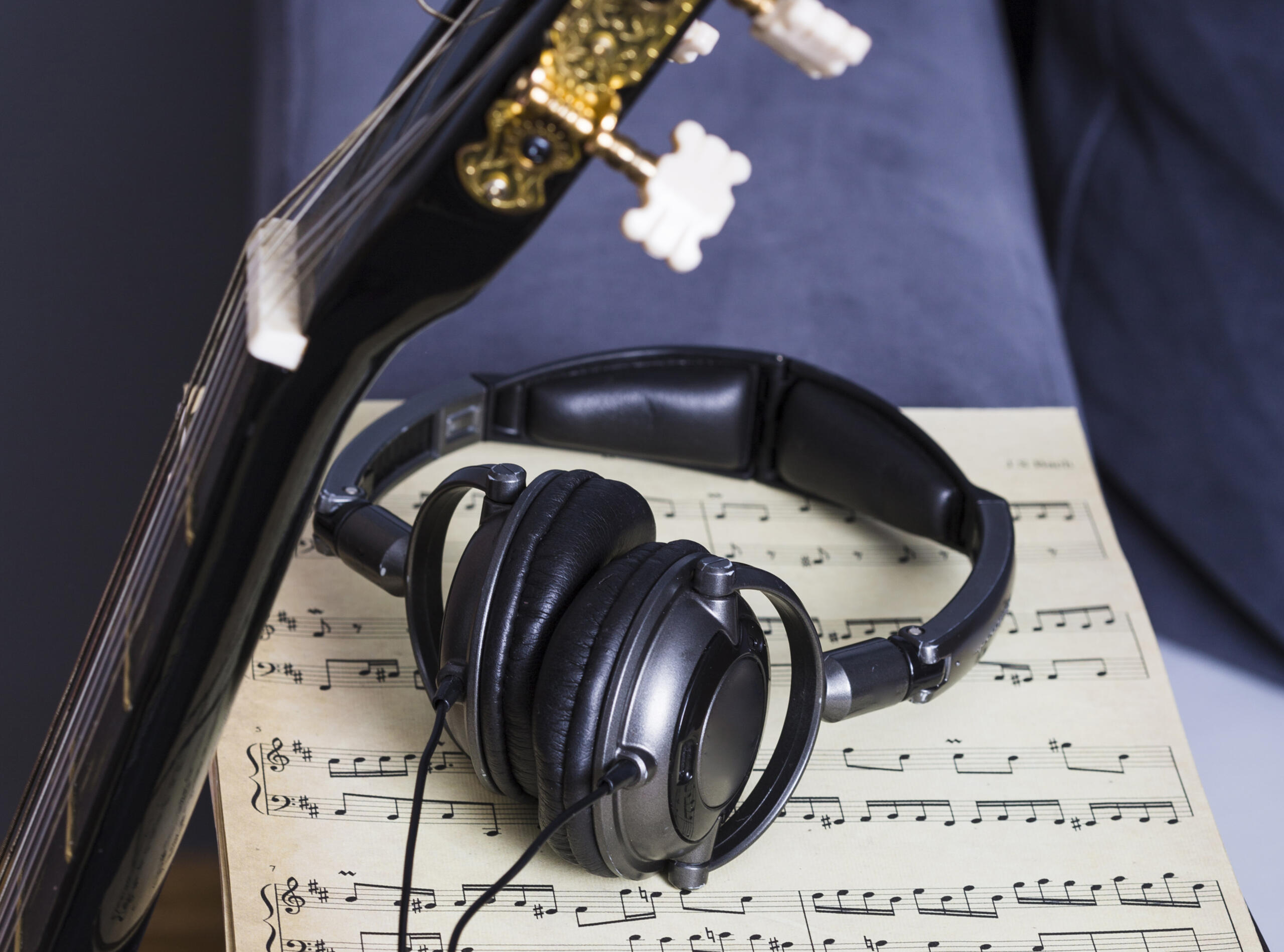 audífonos junto a guitarra y partituras sobre un sofa