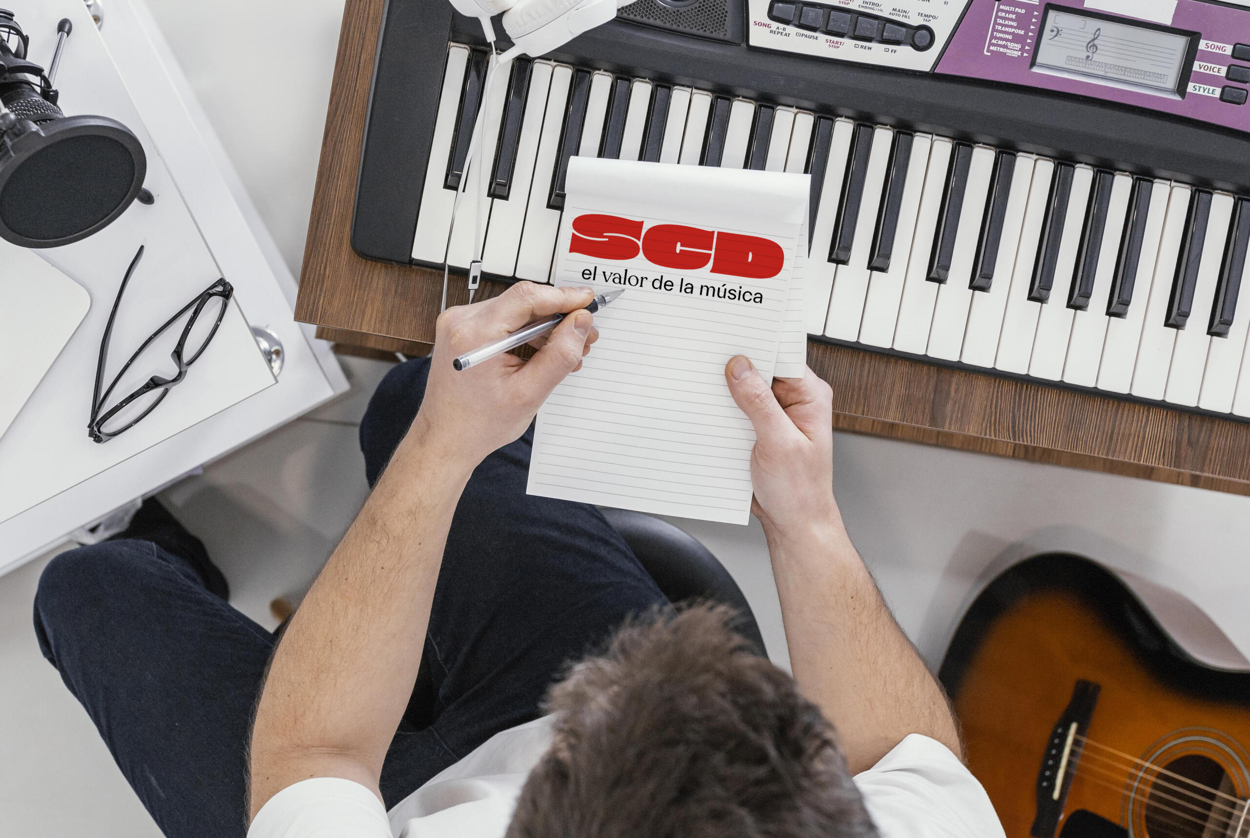 toma cenital de chico componiendo musica en una libreta con el logo de la SCD Chile