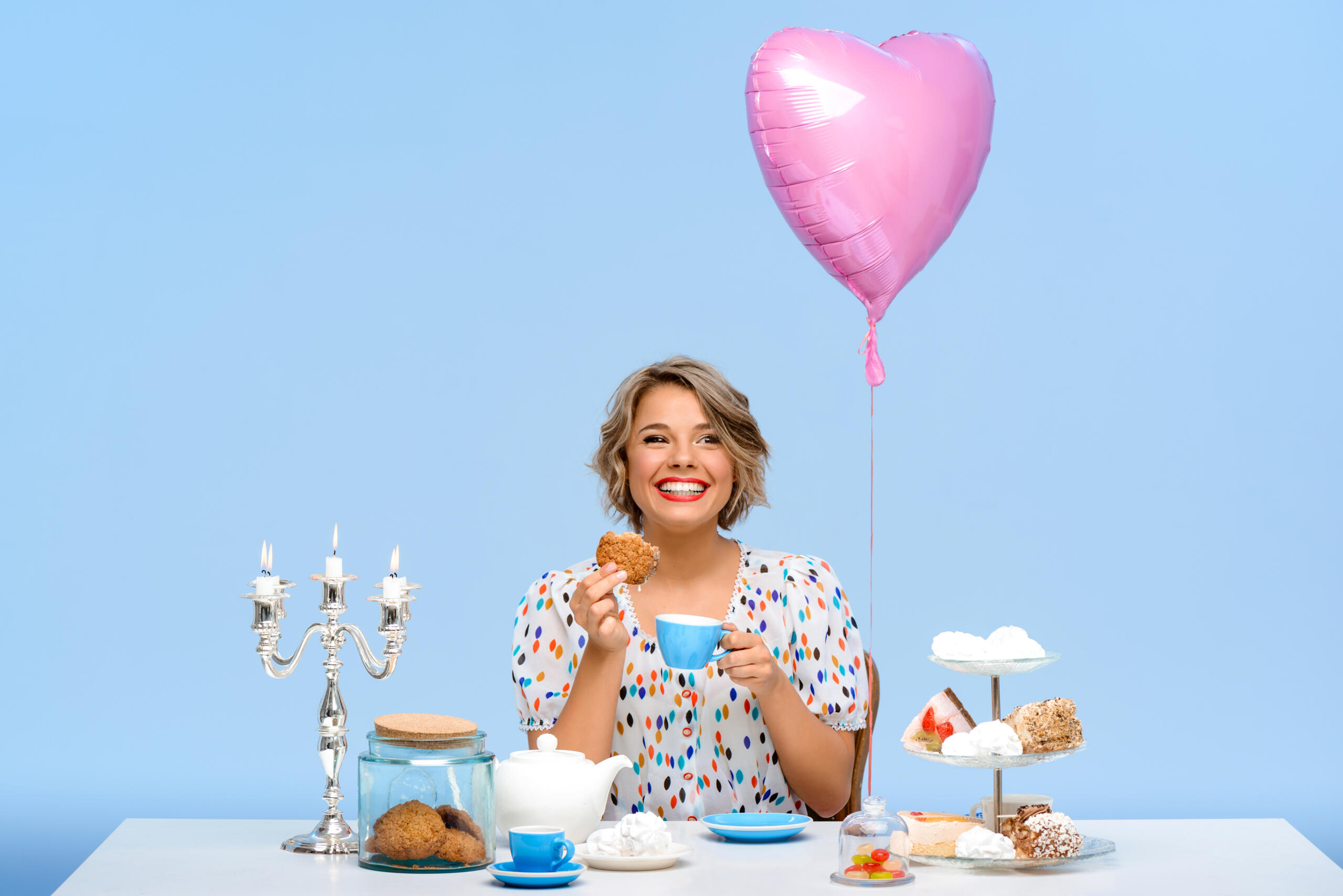 mujer sonriente con una mesa decorada y un globo de corazón rosado