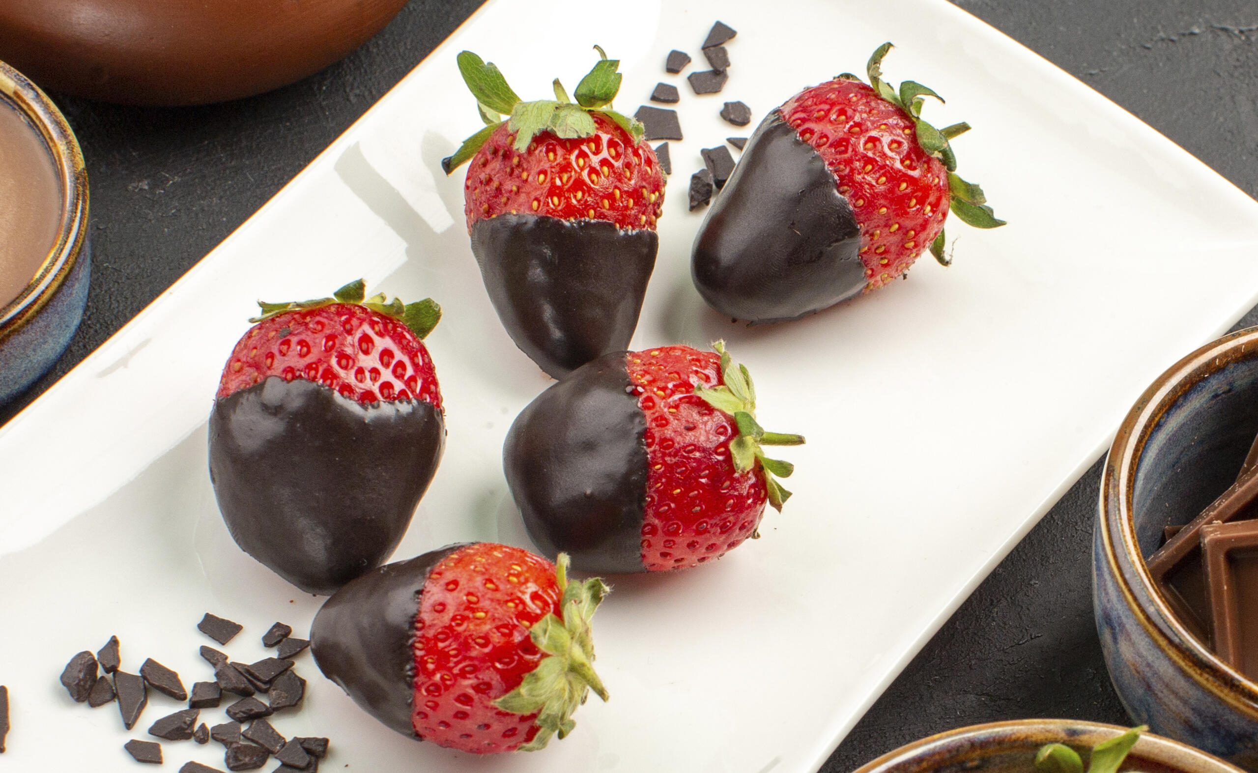 toma detalle de unas fresas con baño de chocolate en una bandeja rectangular blanca