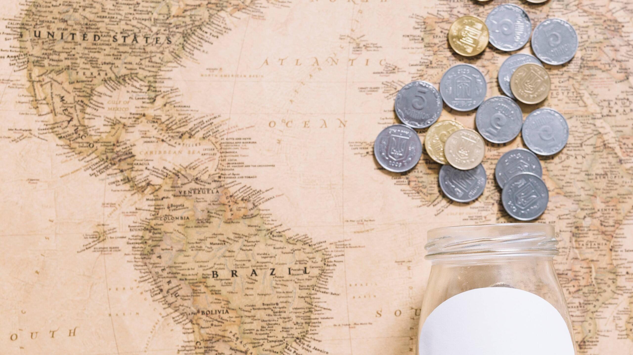 toma cenital de un mapa mundi antiguo junto a monedas dispersas sobre este