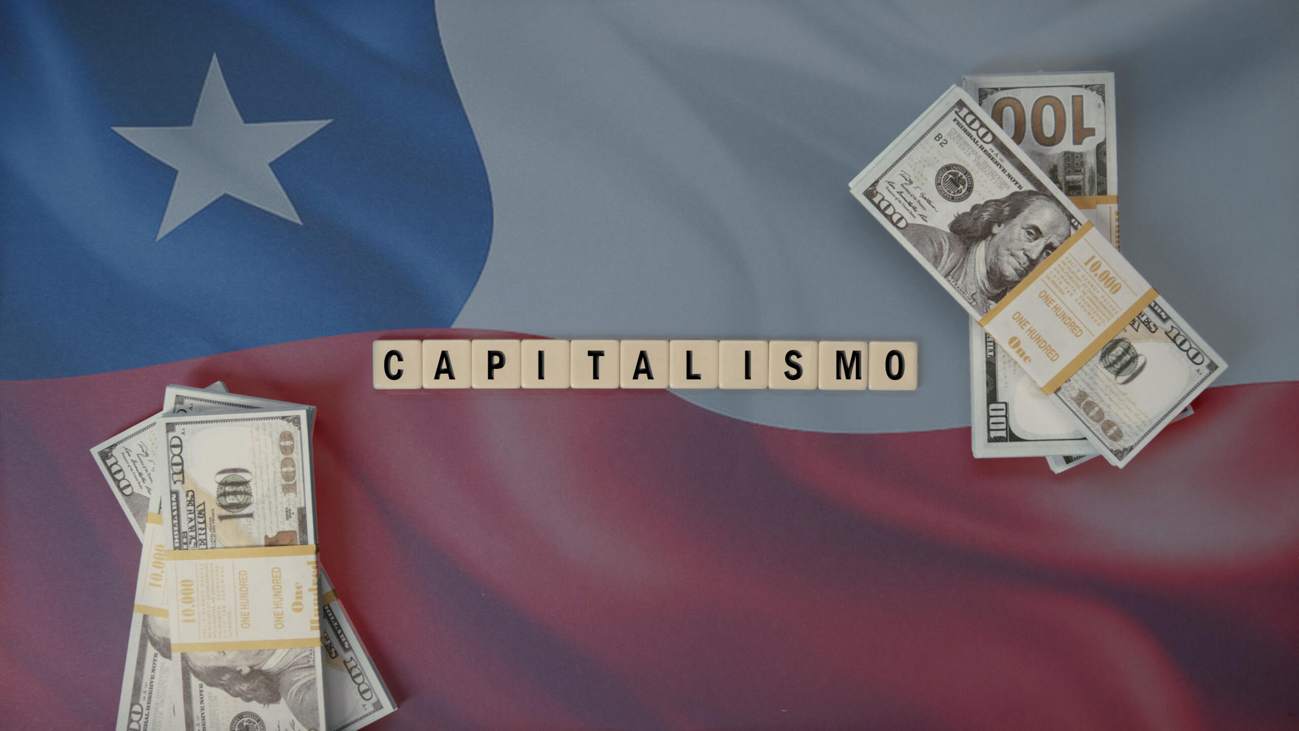 toma cenital con fondo de bandera chilena con fichas de scrabble formando palabra CAPITALISMO