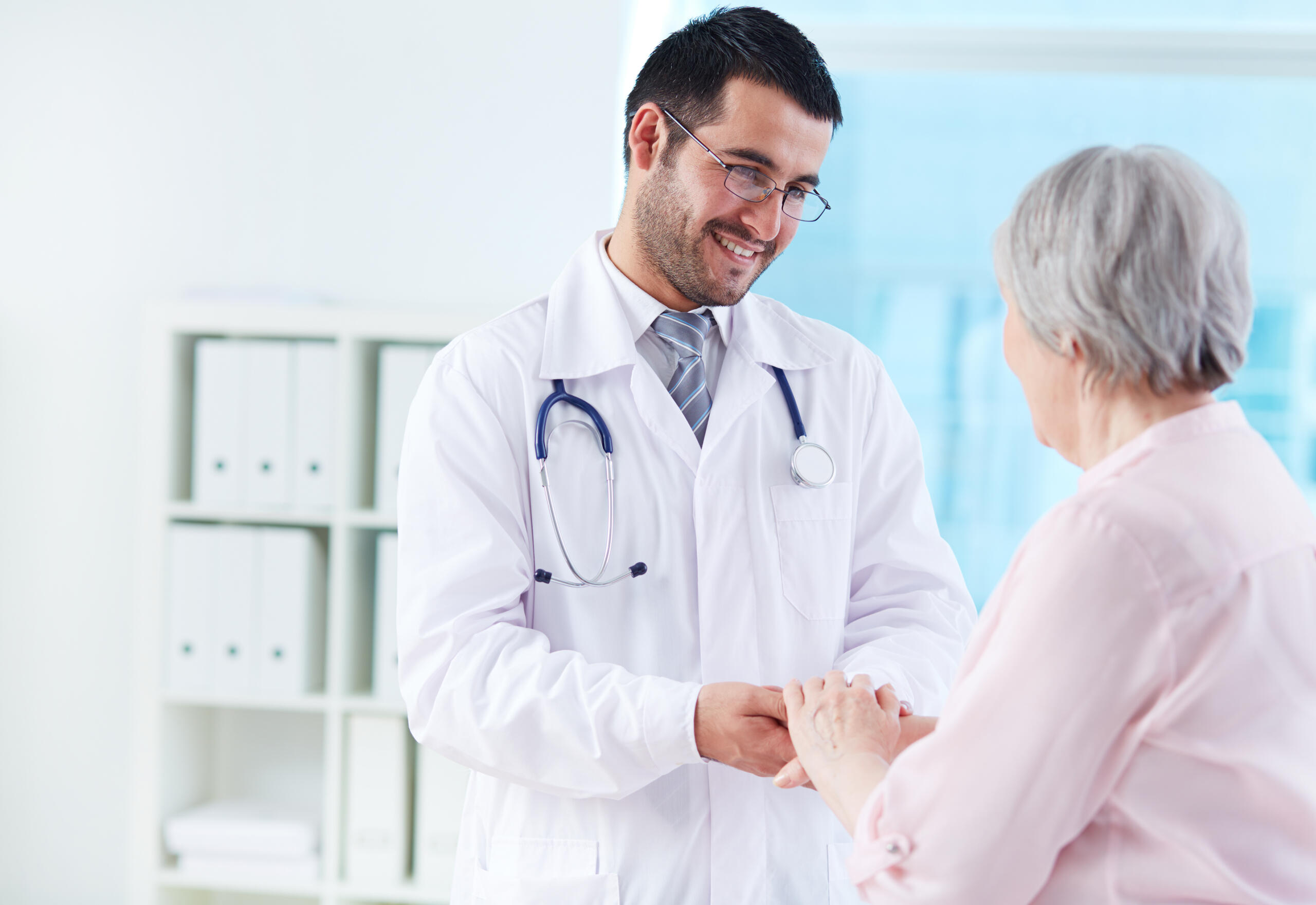 Doctor sonriente sosteniendo la mano de una paciente anciana
