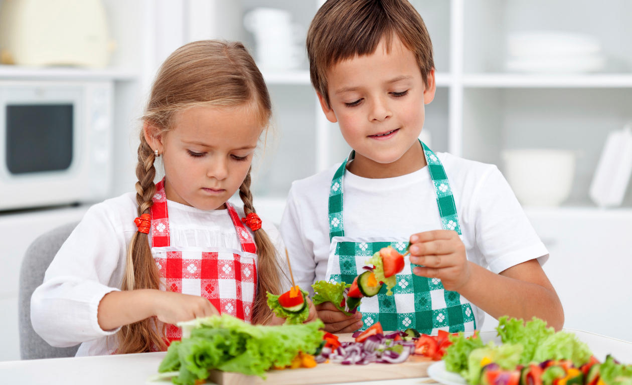 Niños elaborando un plato de fruta en al cocina.