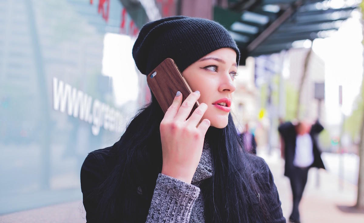 Mujer hablando por teefono celular vistiendo gorro, bufanda y abrigo.