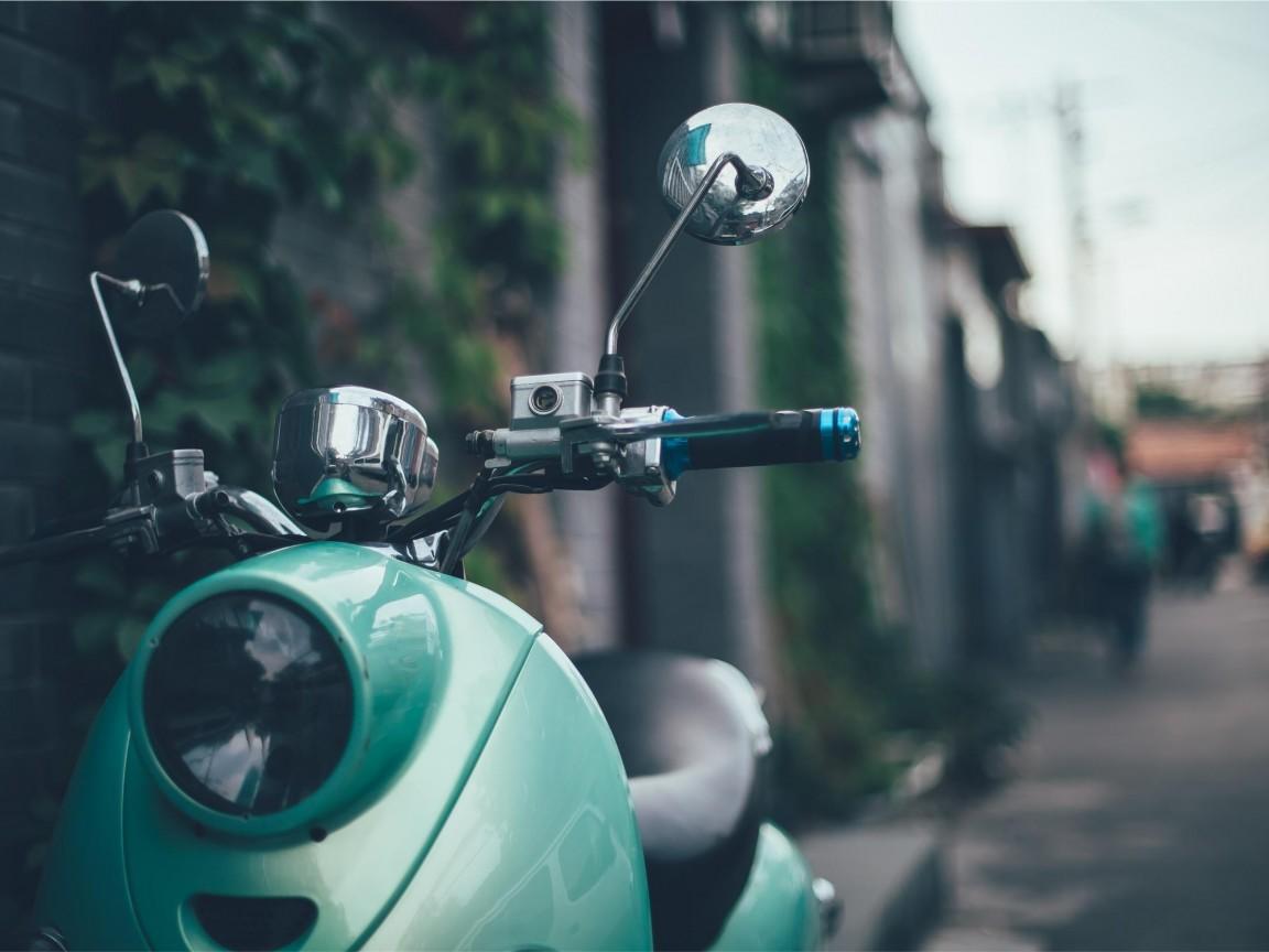 Vespa verde esmeralda sobre un fondo difuminado.