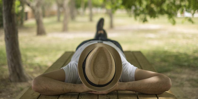 Hombre con sombrero acostado boca arriba sobre una tabla