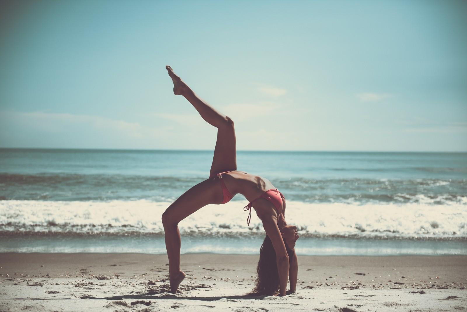 Chica en la playa realizando ejercicio.