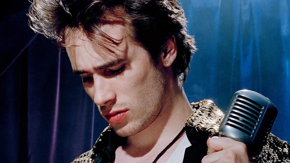 Jeff Buckley mirando hacia abajo con un micrófono en la mano