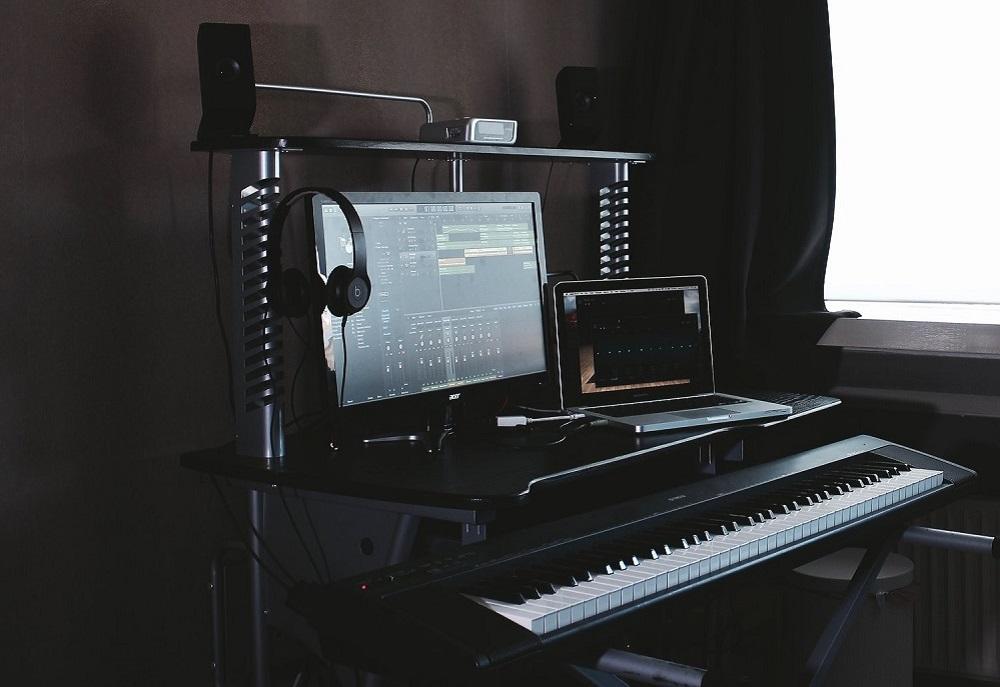Piano digital en un escritorio junto con una pantalla de PC y una tablet.