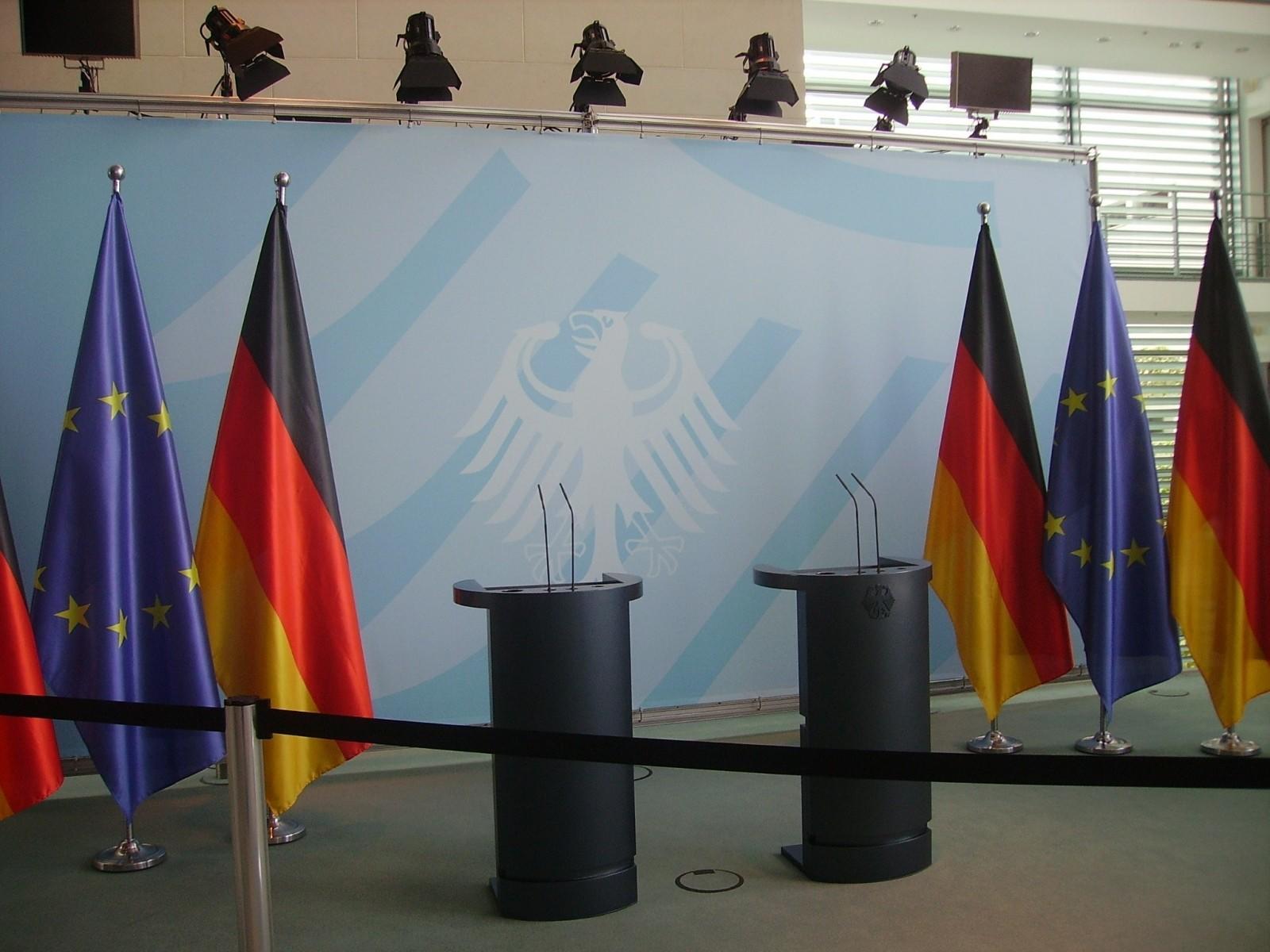 Estrado para debates y atrás banderas de Alemania y la Unión Europea