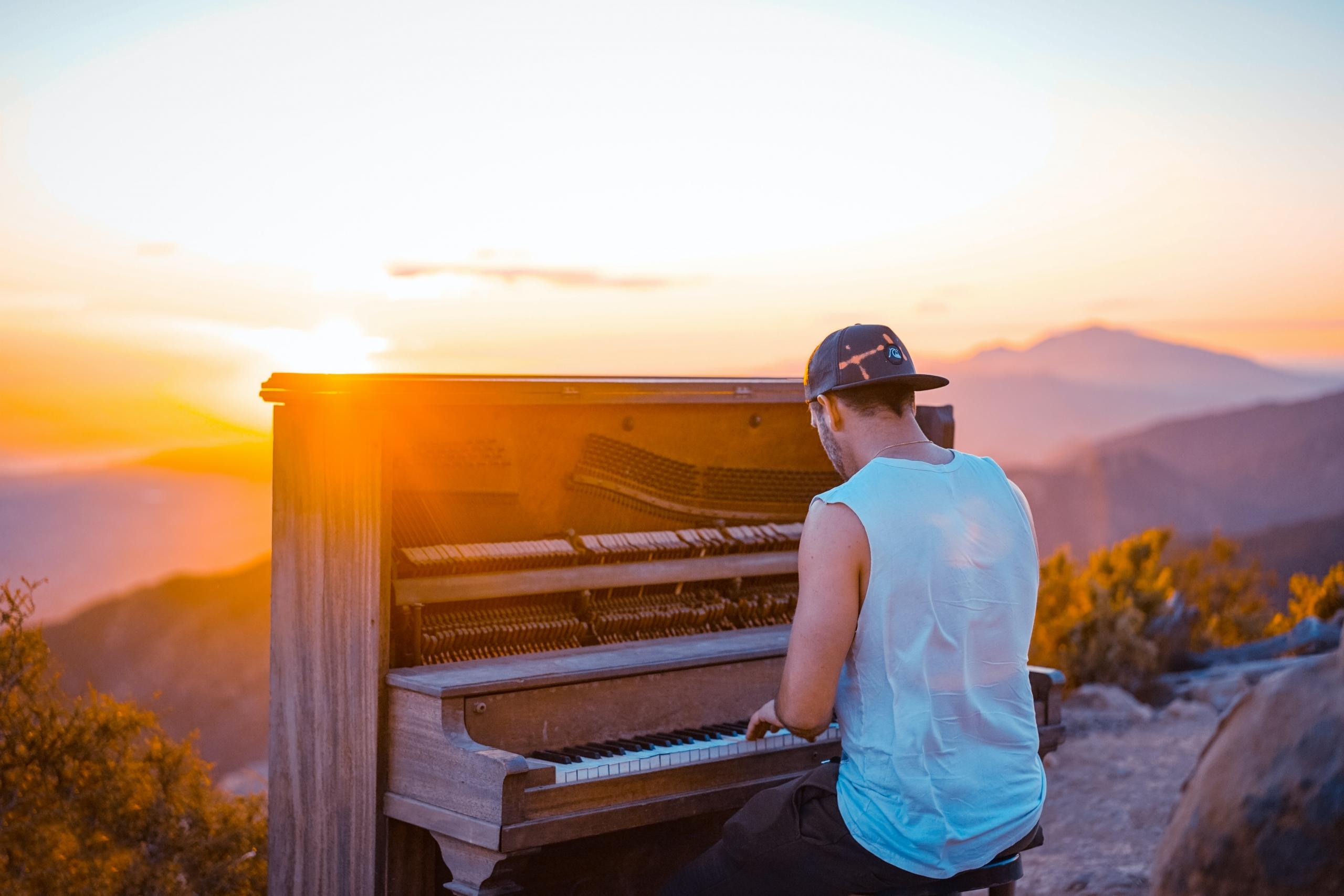 Joven tocando un piano bajo la puesta del sol.