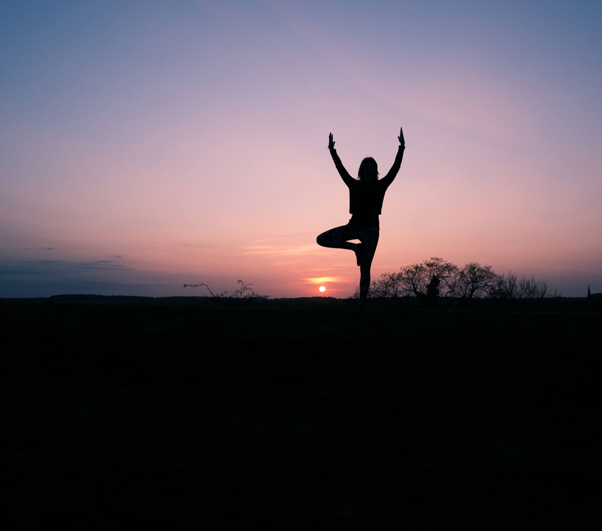 Silueta de una mujer practicando yoga, en el atardecer.