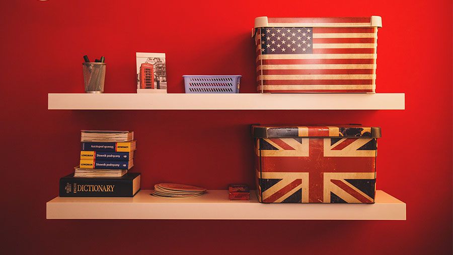Estante con dos cajas que tienen la bandera de Inglaterra y Estados Unidos, junto a unos libros.