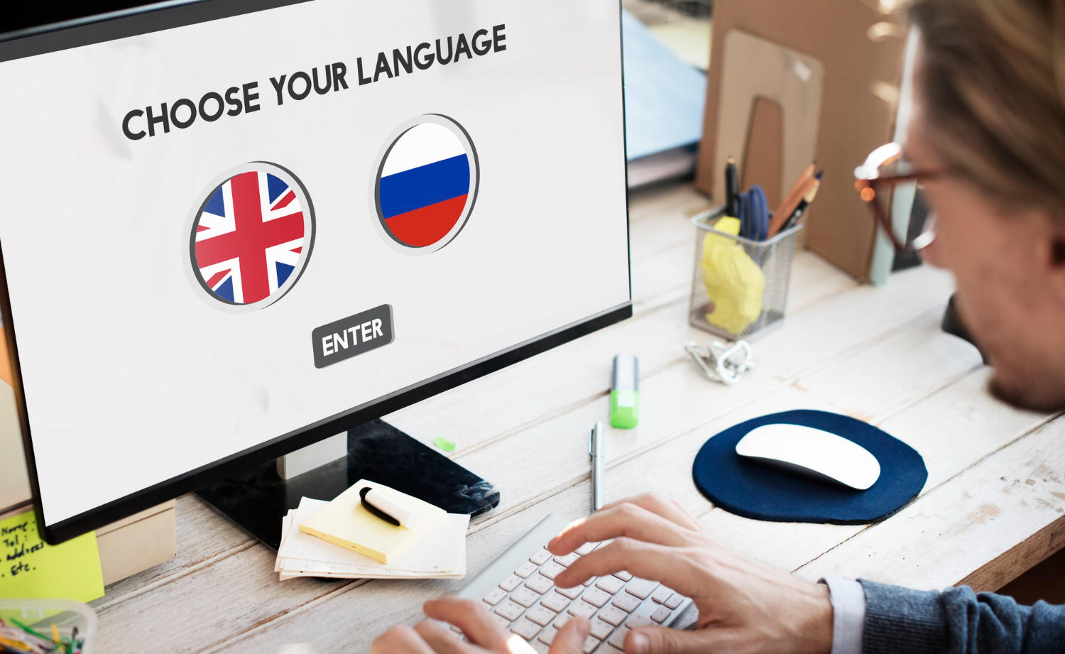 Hombre frente a la pantalla de un PC que tiene abierta una página de traductor ingles- ruso