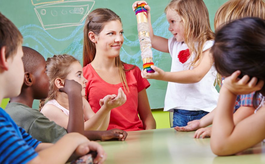 Profesora sonriendo frente a un grupo de niños.