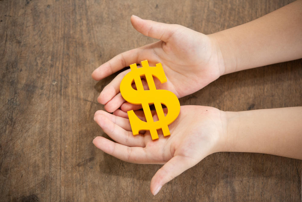 Manos tomando un signo pesos amarillo