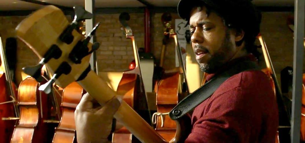 Victor Wooten interpretando el bajo, al fondo unos contrabajos