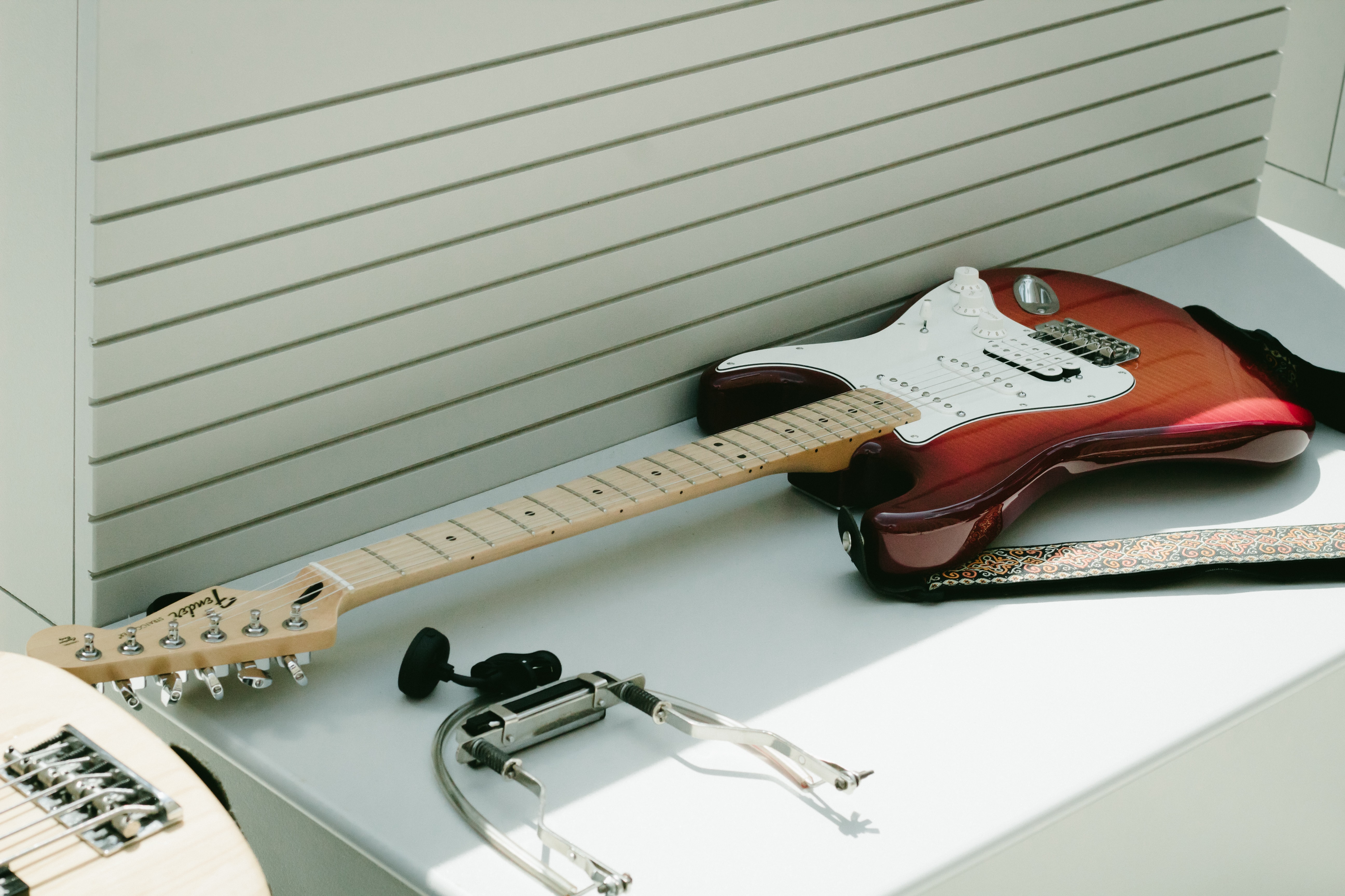Guitarra fender de color blanco y madera sobre superficie blanca