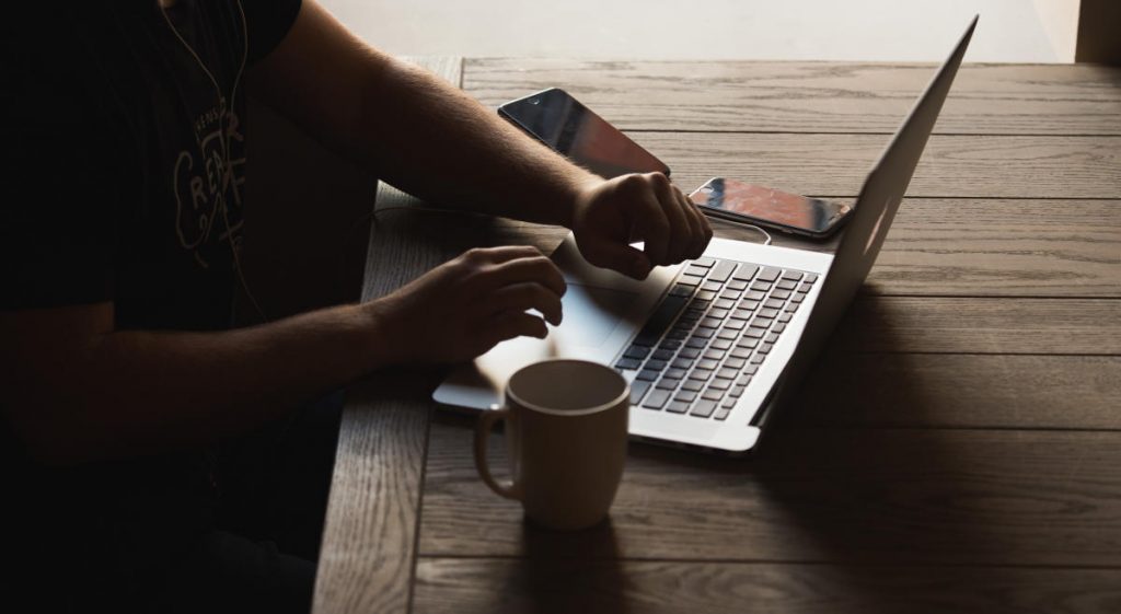 Persona con su laptop y una taza de café estudiando