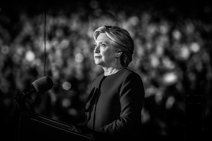 Clinton con la mirada hacia el público, frente a un micrófono lista para dar un discurso.