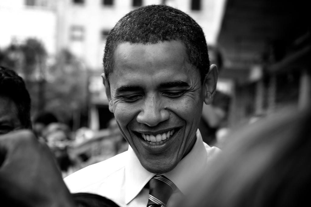 Obama con la mirada baja y una gran sonrisa en su rostro. 