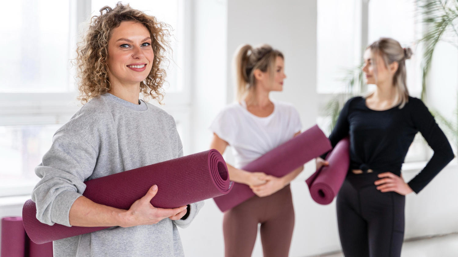 Mujeres sonriendo con esterillas de yoga moradas