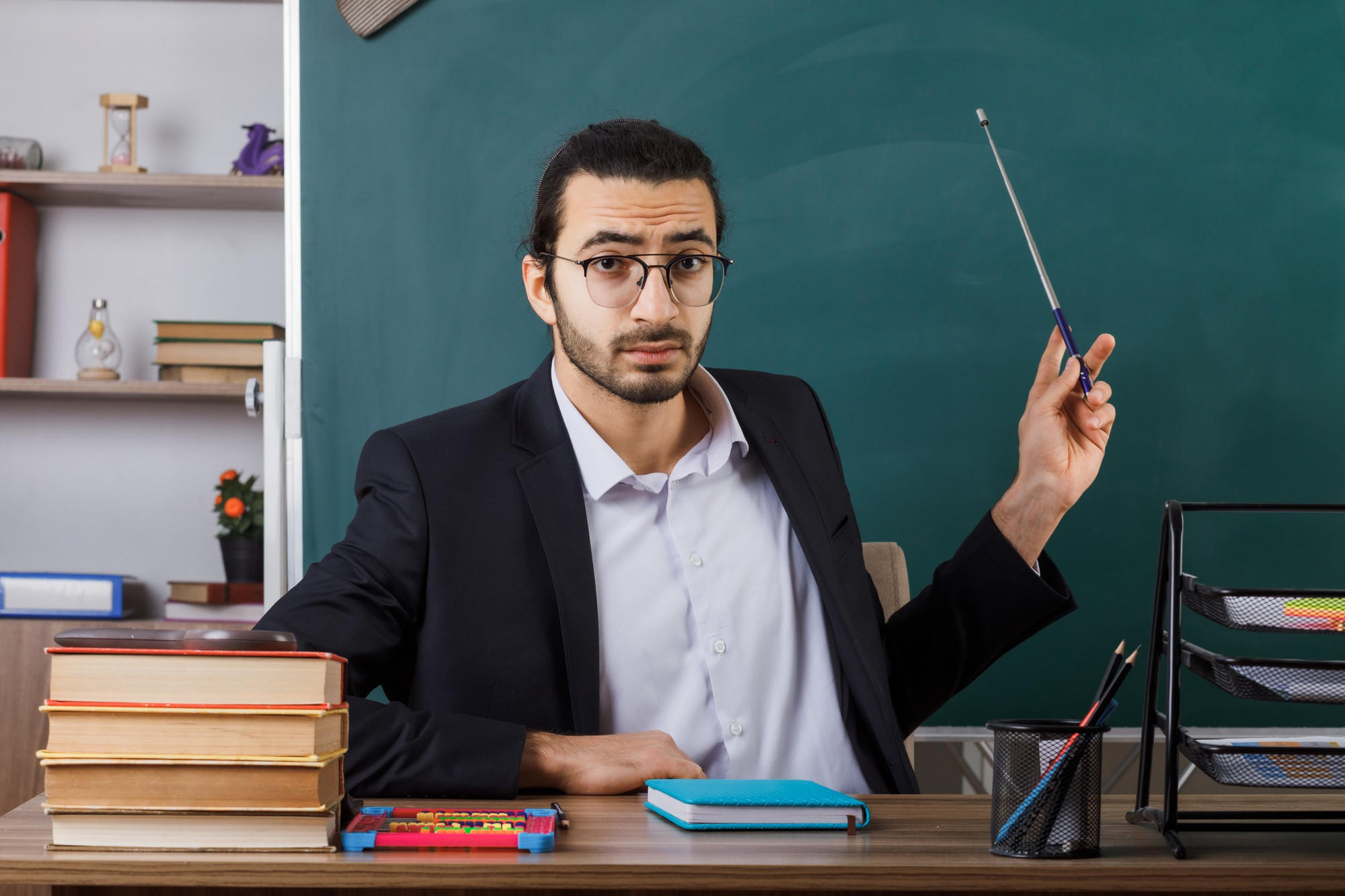 Profesor de gafas señala hacia el tablero