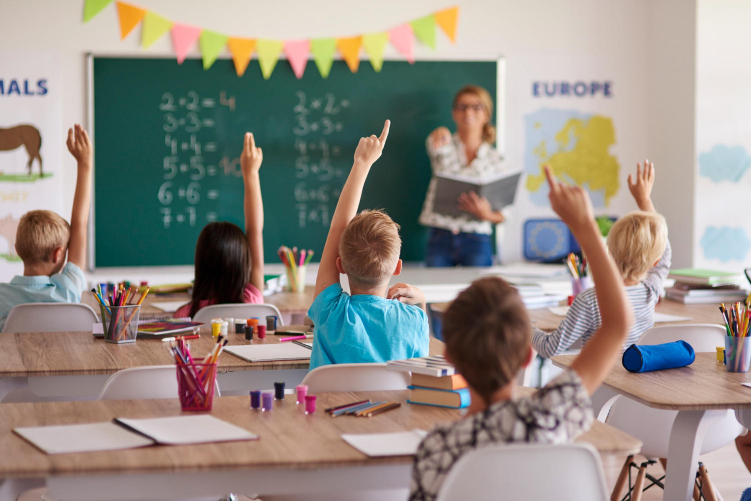 Profesora haciendo participar a los alumnos en clase, alumnos levantando la mano