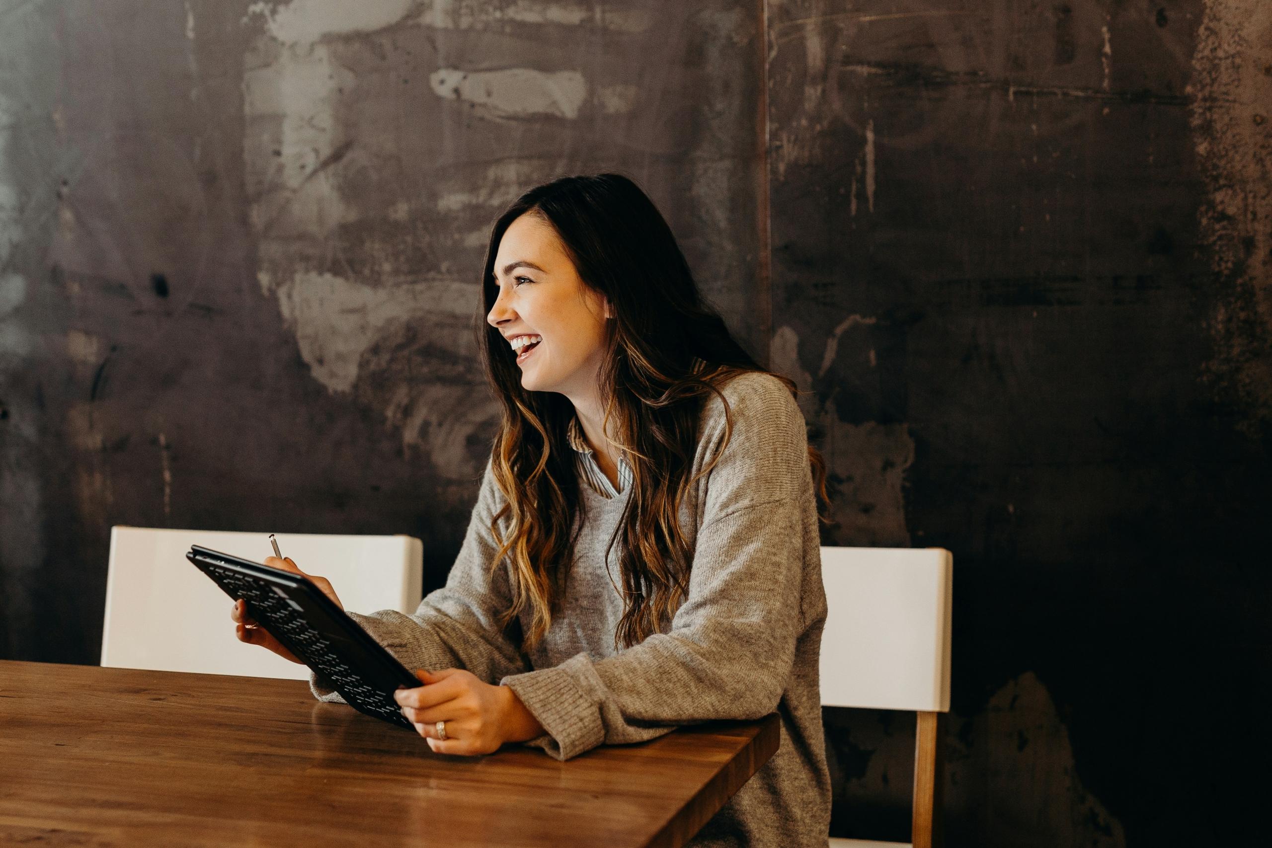 Imagen de una mujer sonriendo, mientras revisa vacantes en linkedin