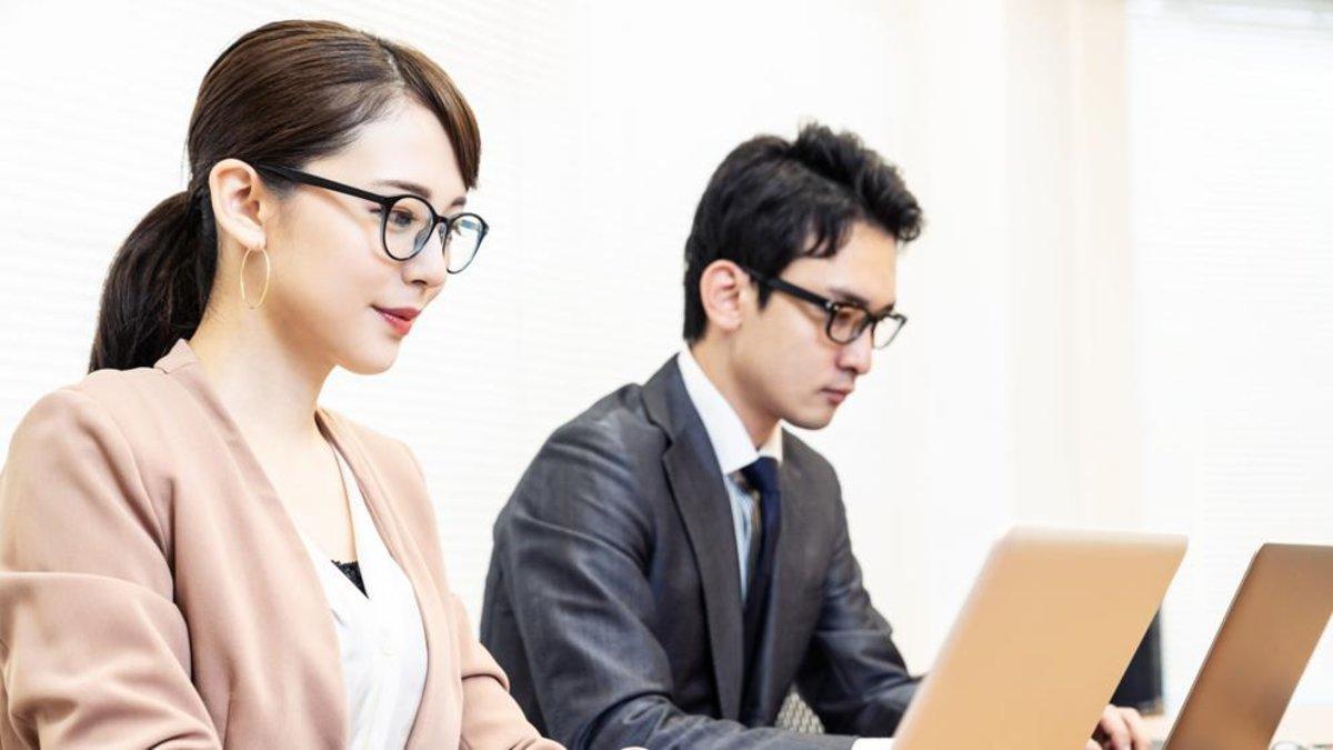 Hombre y mujer asiáticos trabajando frente a portátiles.
