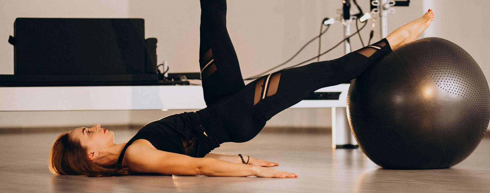 Chica haciendo pilates con una pelota.