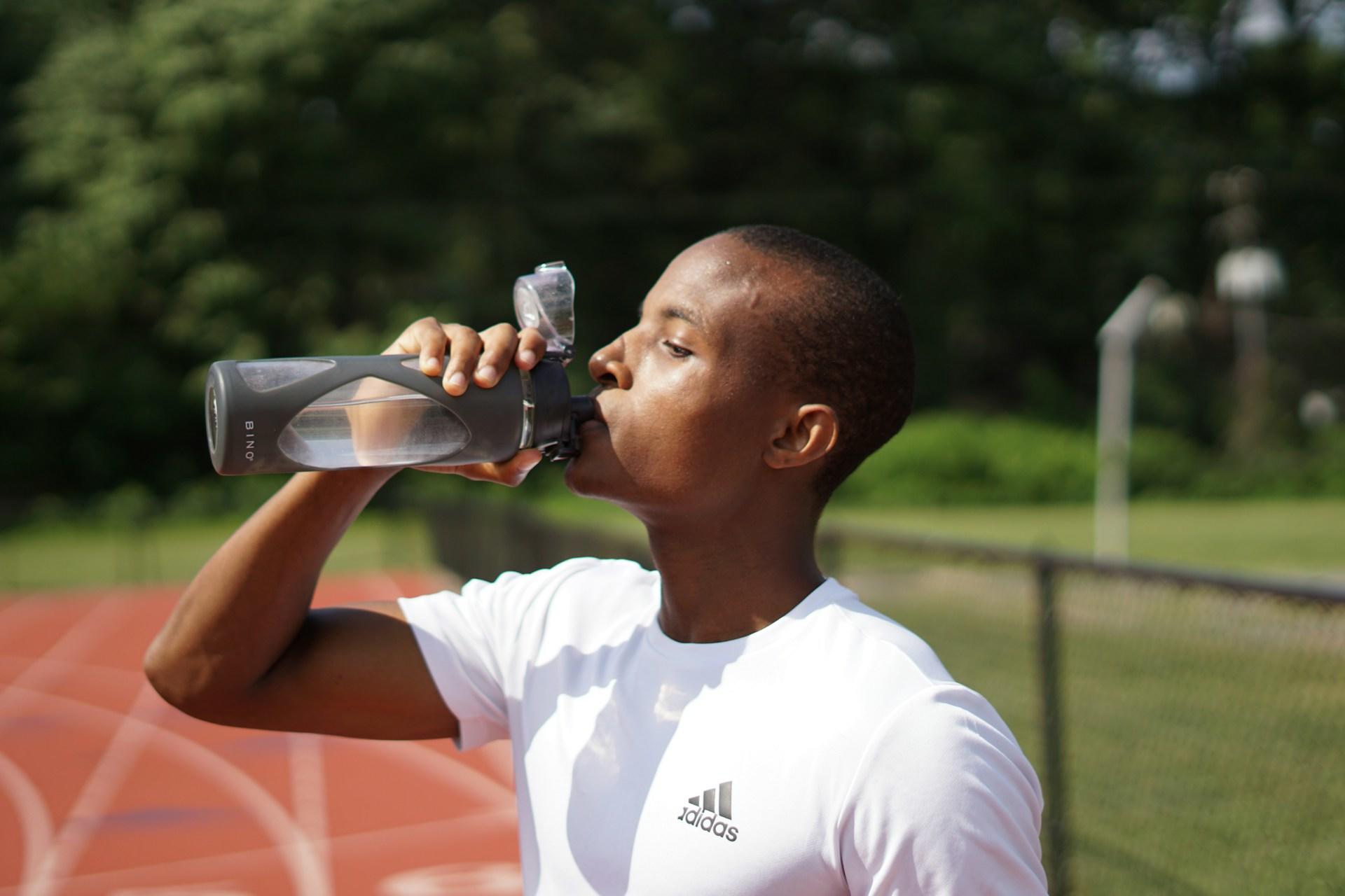 Joven tomando agua después de correr.